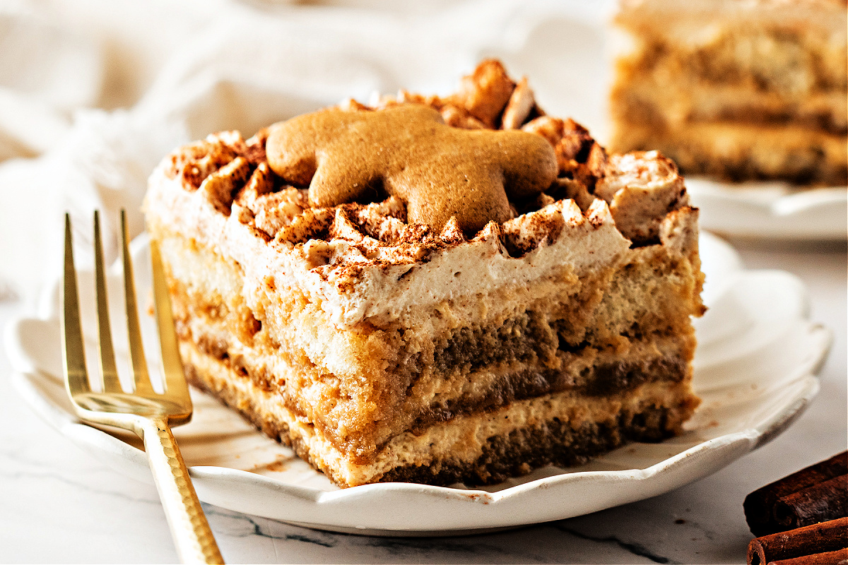 Slice of gingerbread tiramisu on a plate with gingerbread cookie and visible layered texture. A plated slice of gingerbread tiramisu topped with a small gingerbread cookie, showing the espresso-soaked layers and spiced mascarpone cream with cocoa dusting.