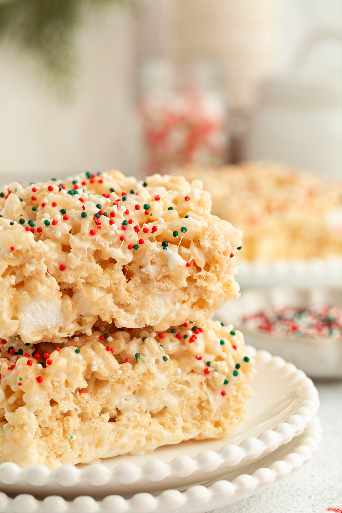 Stacked sugar cookie–flavored Rice Krispie treats showing a soft marshmallow center and festive red, green, and white sprinkles.