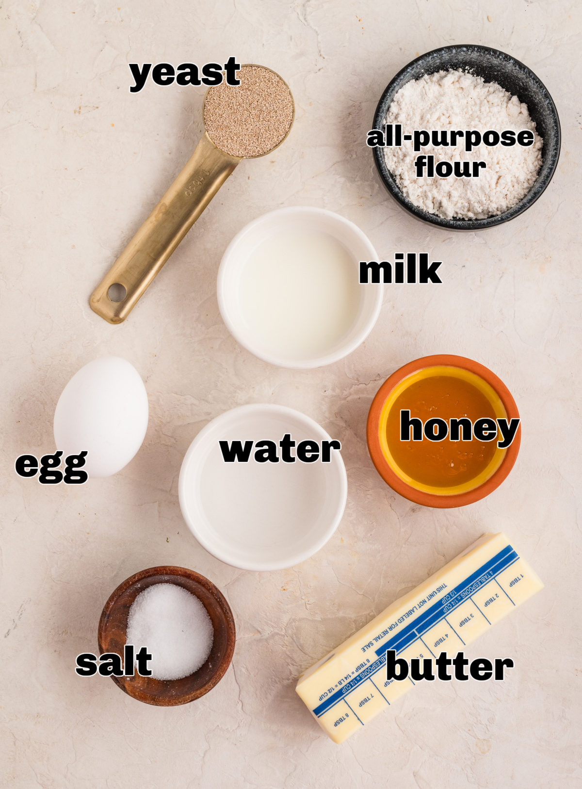 Measured ingredients for pull-apart rolls including flour, yeast, milk, water, honey, egg, salt, and butter.