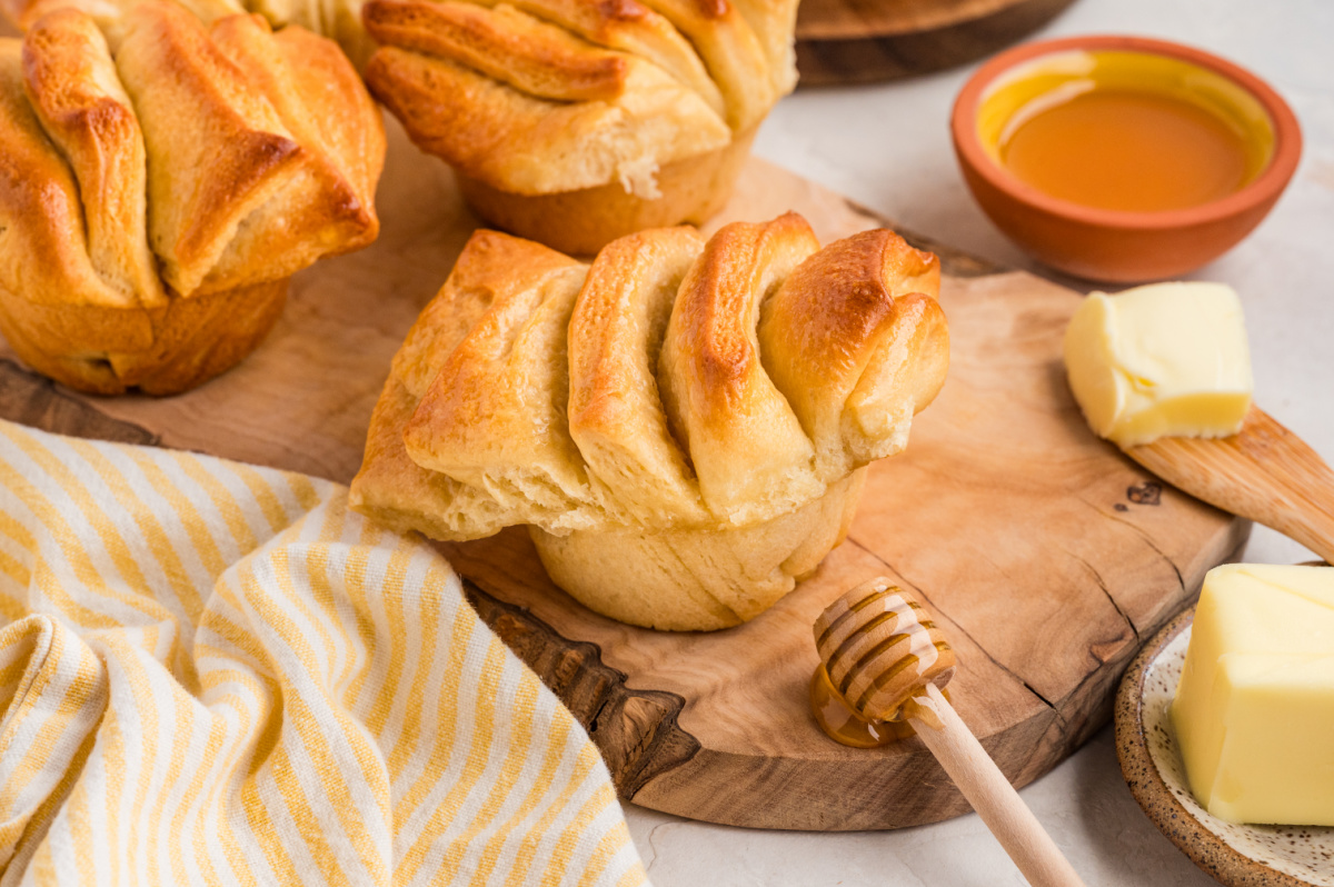 Soft pull-apart rolls with visible layers and a fluffy interior resting on a wooden board.