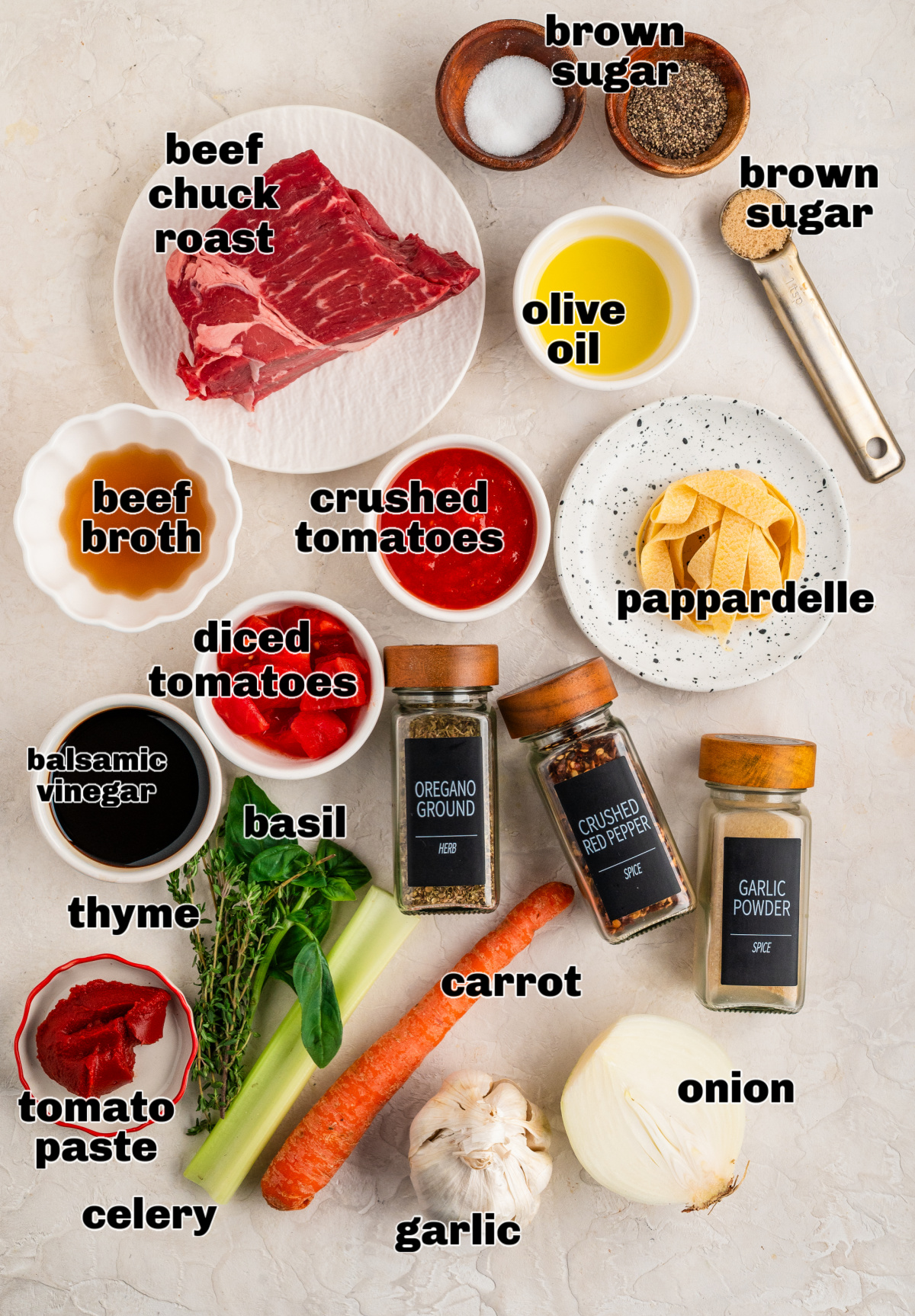 Ingredients arranged for making a slow-cooked beef ragù with pappardelle. Ingredients for an oven-braised beef ragù laid out on a counter, including chuck roast, tomatoes, herbs, aromatics, oil, seasonings, and pappardelle.