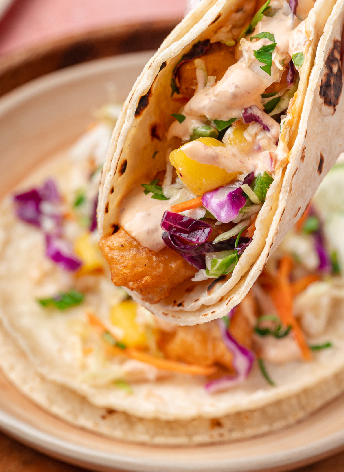Beer-Battered Fish Tacos with Mango Slaw Beer-battered fish tacos with mango slaw and chipotle lime sauce folded into warm corn tortillas.