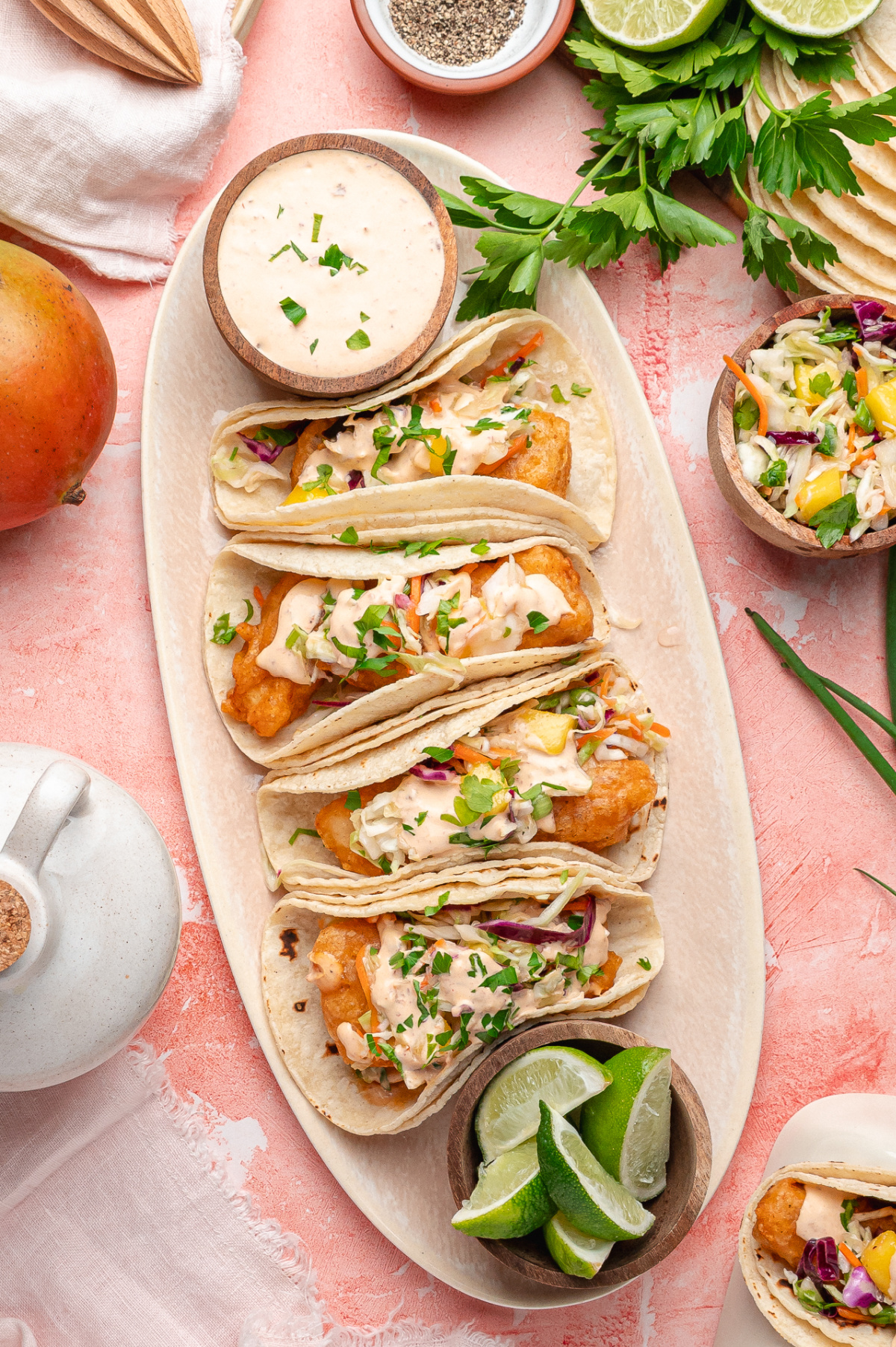 Beer-Battered Fish Tacos with Mango Slaw and Chipotle Lime Sauce Beer-battered fish tacos filled with crispy cod, mango slaw, and chipotle lime sauce served with lime wedges.