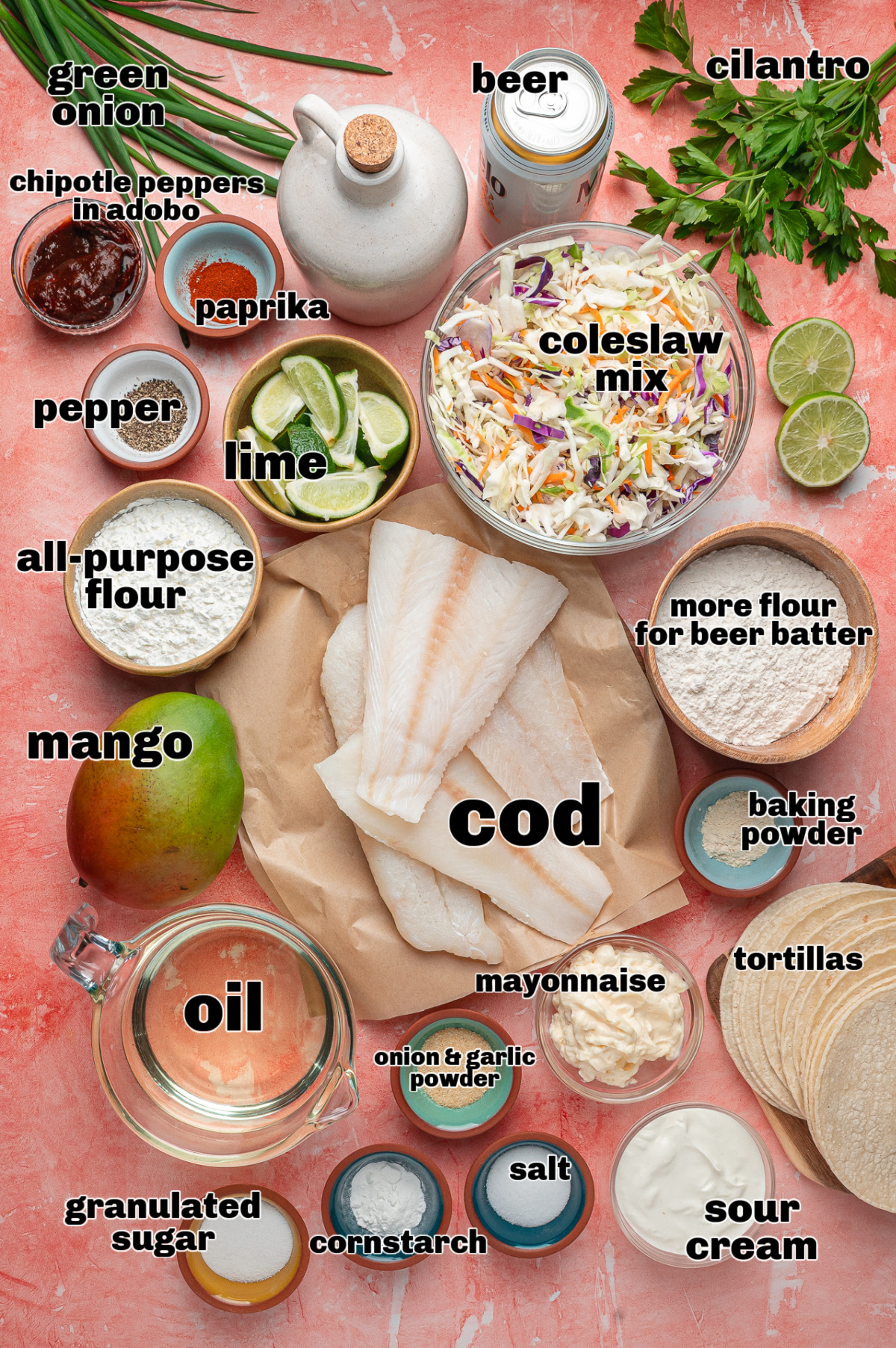 Ingredients for Beer-Battered Fish Tacos with Mango Slaw Ingredients for beer-battered fish tacos laid out, including cod, coleslaw mix, mango, beer, tortillas, and chipotle lime sauce components.