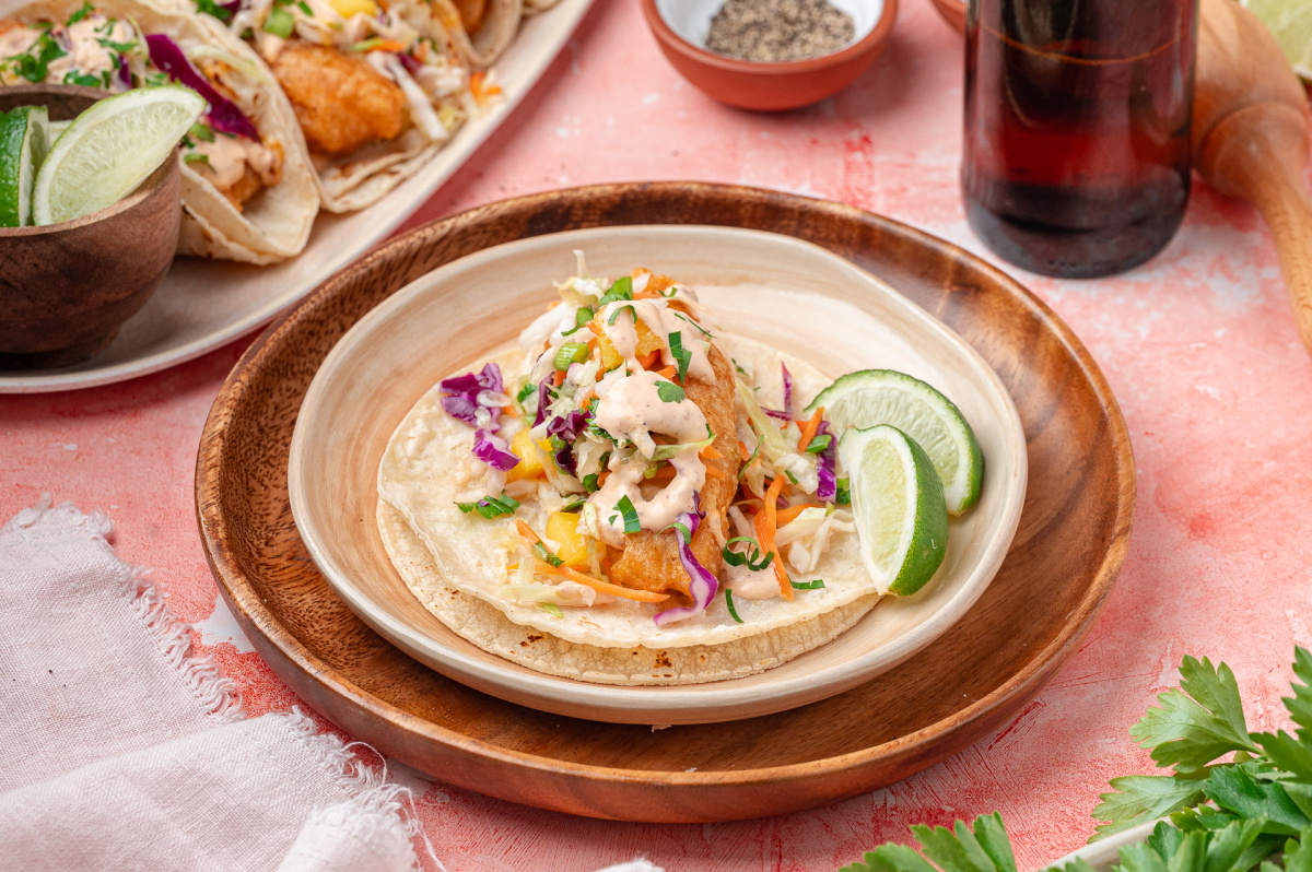 Fried Cod Tacos with Mango Slaw Fried cod tucked into corn tortillas with mango slaw, chipotle lime sauce, and fresh lime wedges.