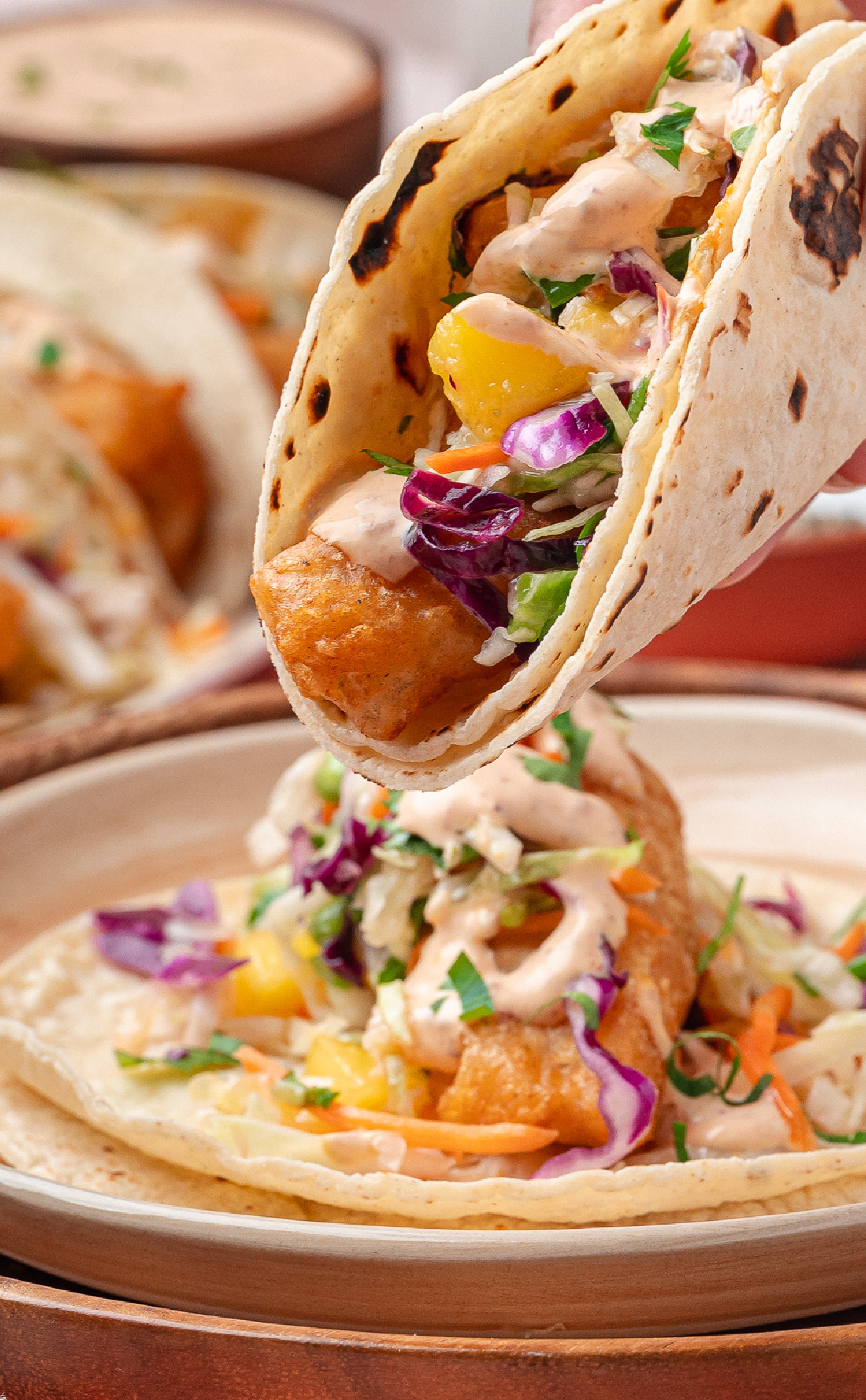 Beer-Battered Cod Taco Close-Up Close-up of crispy beer-battered cod in a corn tortilla with mango slaw and chipotle lime sauce.