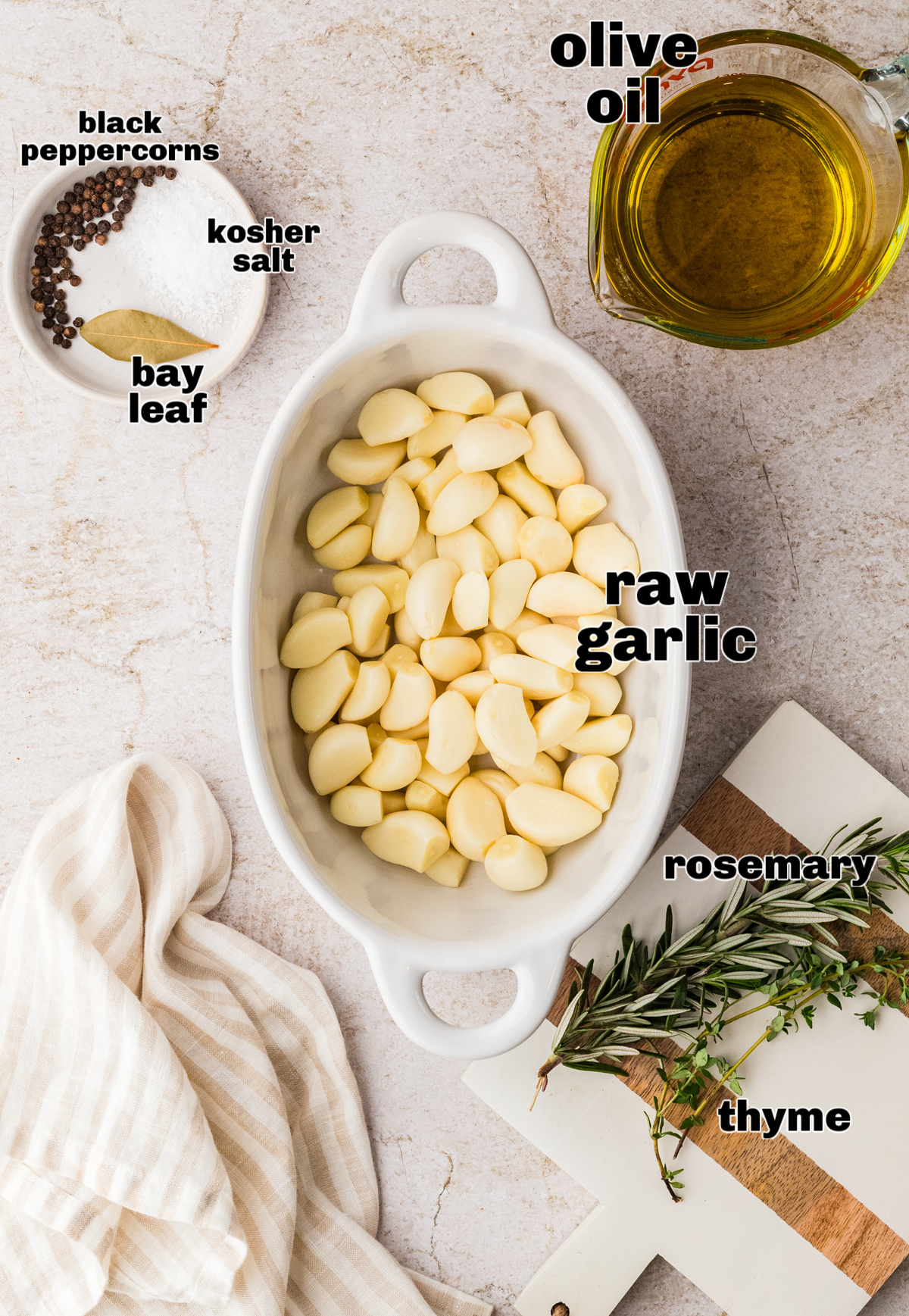 Ingredients for oven-cooked garlic cloves in olive oil. Peeled raw garlic cloves with olive oil, thyme, rosemary, bay leaf, kosher salt, and black peppercorns.