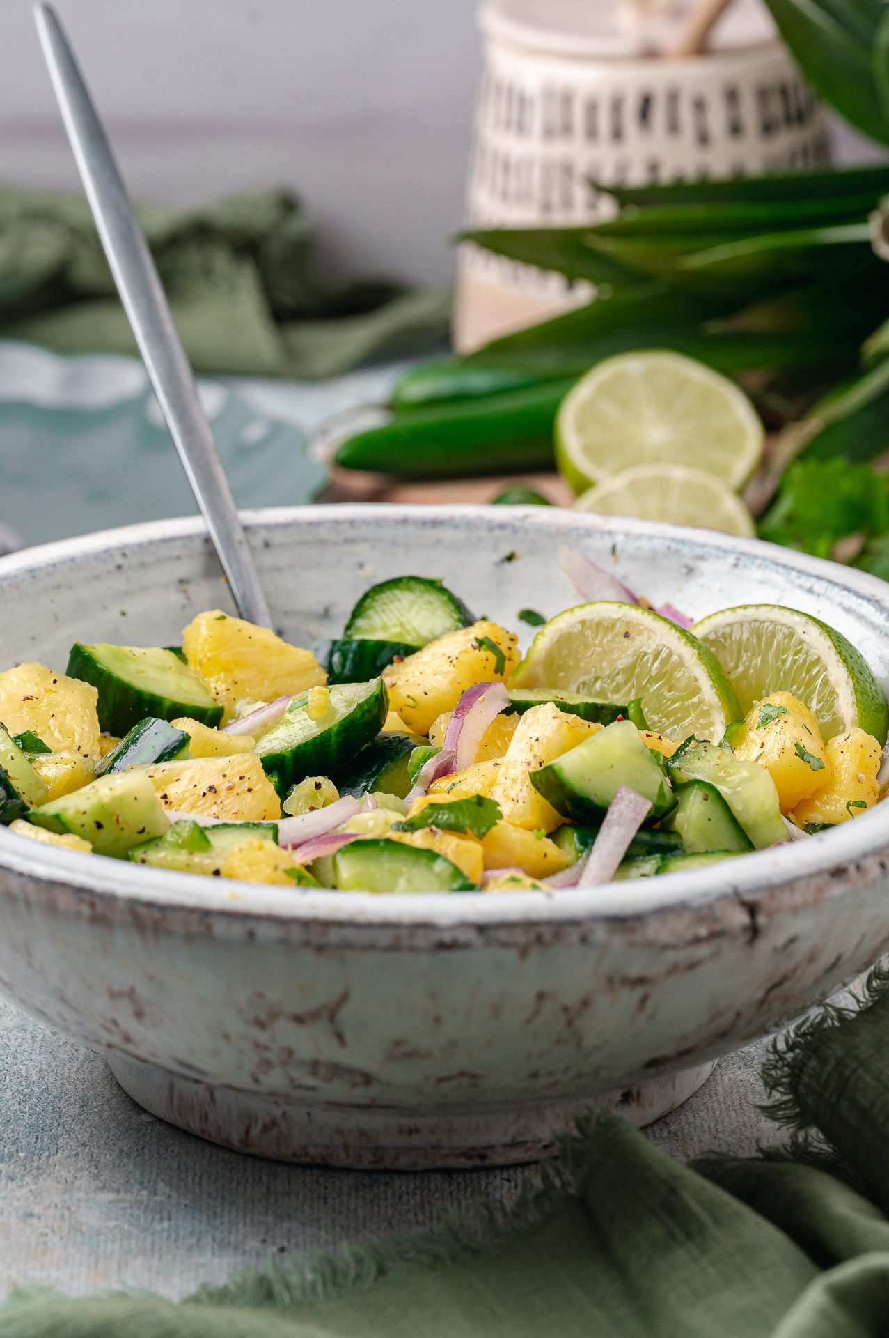 A forkful shows the texture of pineapple, cucumber, and red onion. Forkful of chilled pineapple cucumber salad with pineapple, cucumber, red onion, and cracked black pepper.
