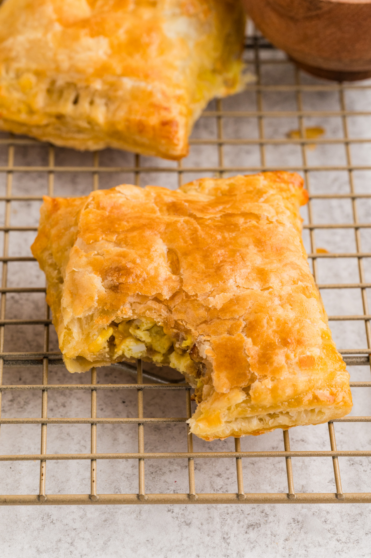 shows the sausage, egg, and cheese filling tucked inside crisp puff pastry layers. a bite taken out of the breakfast pastry with sausage and eggs