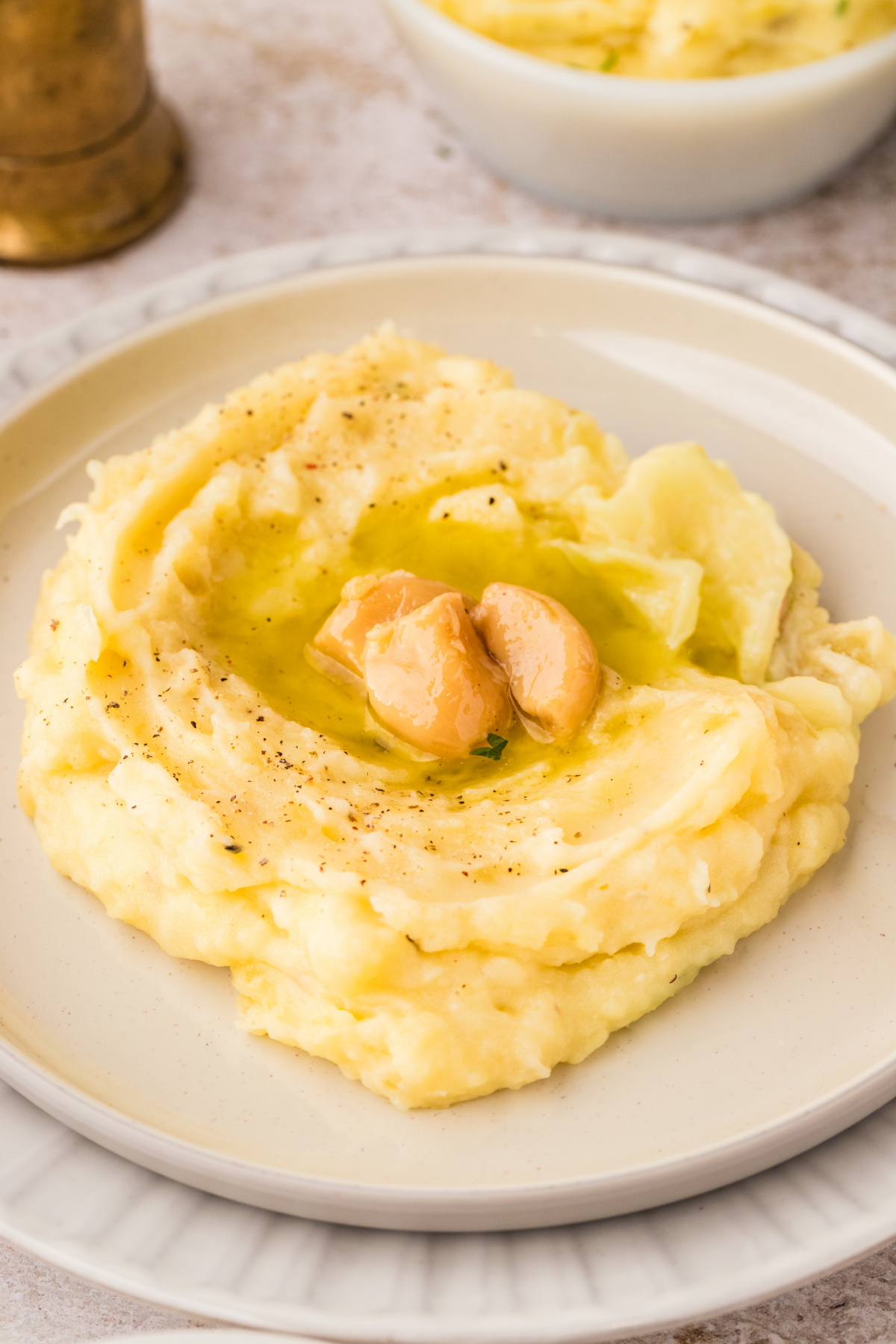 Slow cooker garlic confit mashed potatoes plated with confit garlic cloves and garlic oil pooled in the center, showing a creamy, rich texture.