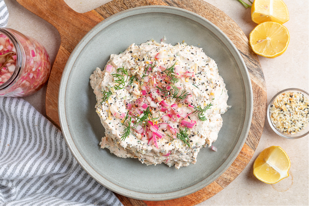 Smoked salmon dip with a creamy texture and pickled red onion topping, ready for serving. Smoked salmon dip with cream cheese, dill, capers, and pickled red onions, shown close up with a spoon ready to scoop.