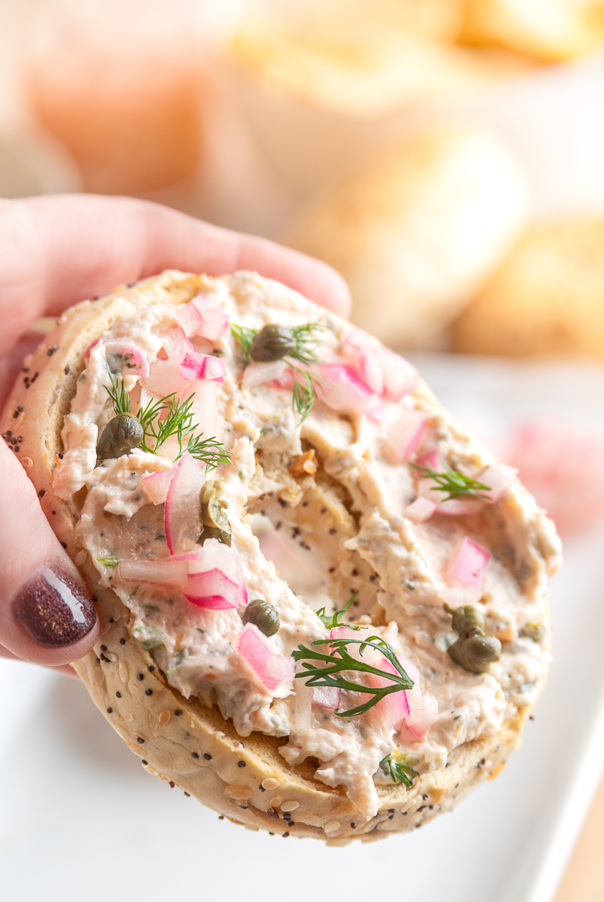 Salmon cream cheese spread served on an everything bagel with pickled red onions and dill. Creamy salmon spread on an everything bagel, topped with capers, pickled red onions, and fresh dill.