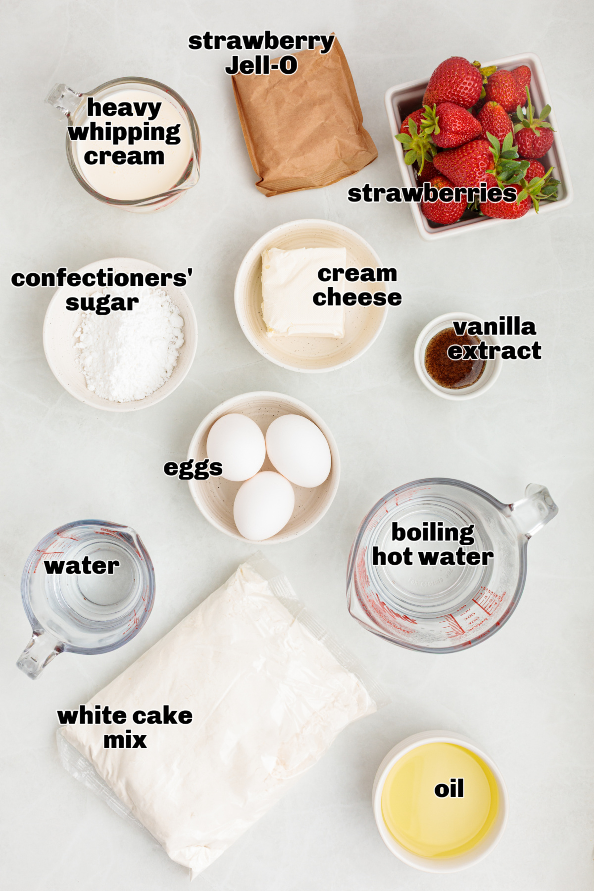 These ingredients are laid out for making a strawberry Jell-O poke cake with fresh strawberries and whipped vanilla cream cheese frosting. Ingredients for strawberry Jell-O poke cake arranged on a light surface, including white cake mix, eggs, oil, water, strawberry gelatin, fresh strawberries, cream cheese, confectioners’ sugar, vanilla extract, and heavy whipping cream.