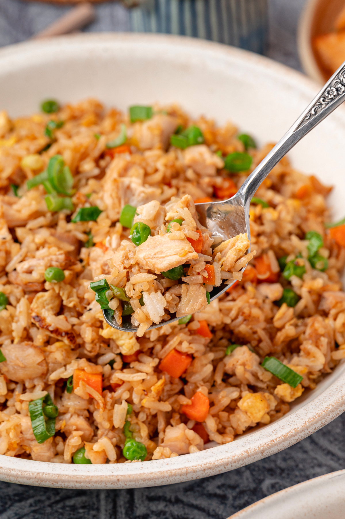 Close-up of fried rice with chicken, scrambled eggs, peas, carrots, and sliced green onions, showing separate grains of rice and tender chicken pieces Fried rice with chicken, eggs, peas, carrots, and green onions served in a bowl