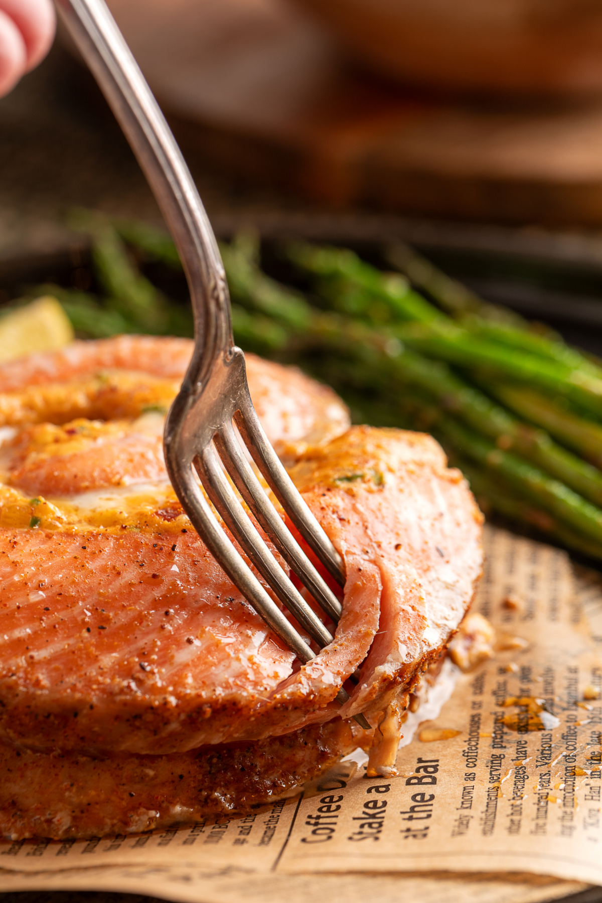 Close-up of a fork cutting into a baked stuffed salmon pinwheel, showing the tender salmon and creamy jalapeño popper-style center. Fork cutting into a baked salmon pinwheel with creamy jalapeño popper filling