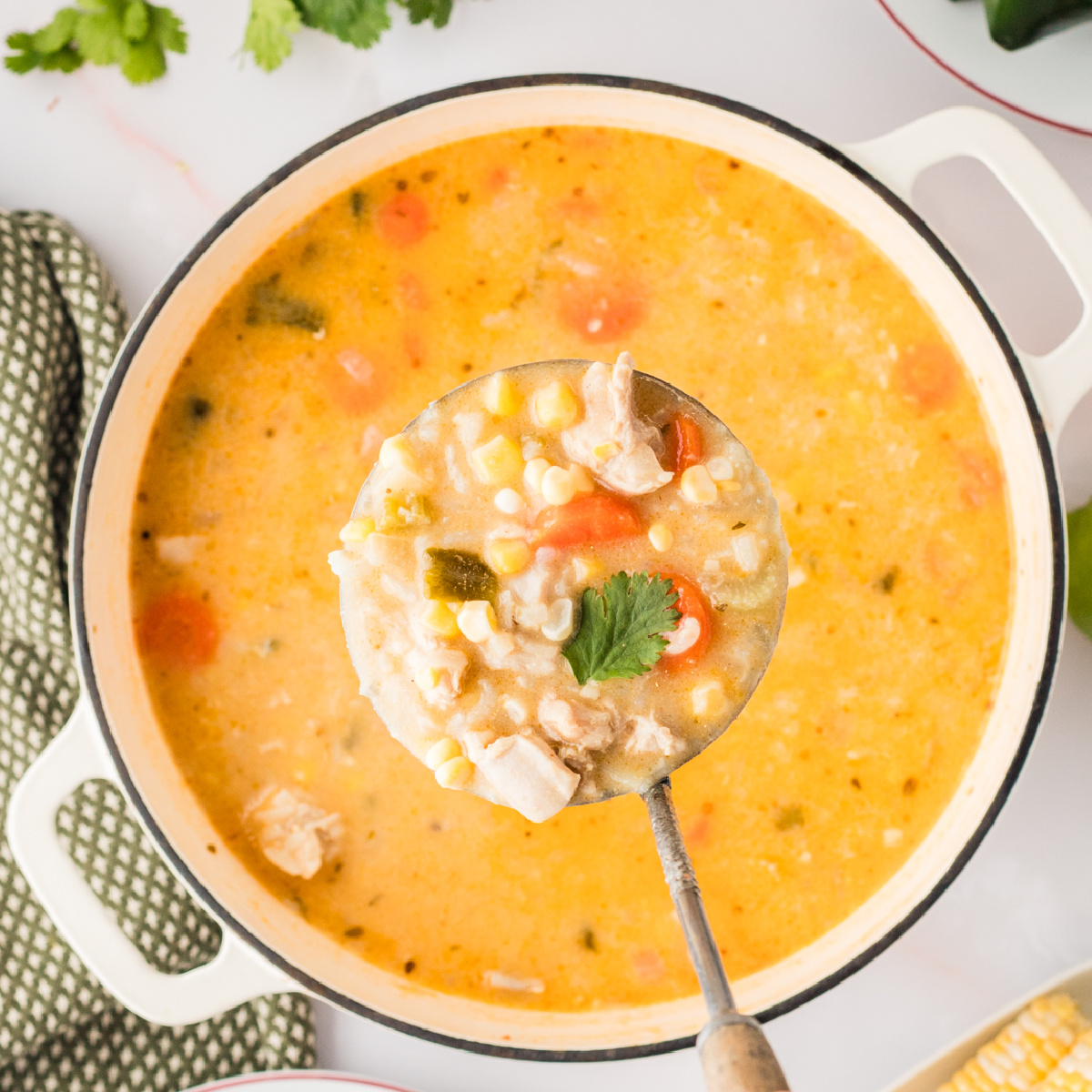 Creamy Chicken and Rice Poblano Soup simmering in a Dutch oven with corn, carrots, and fresh lime