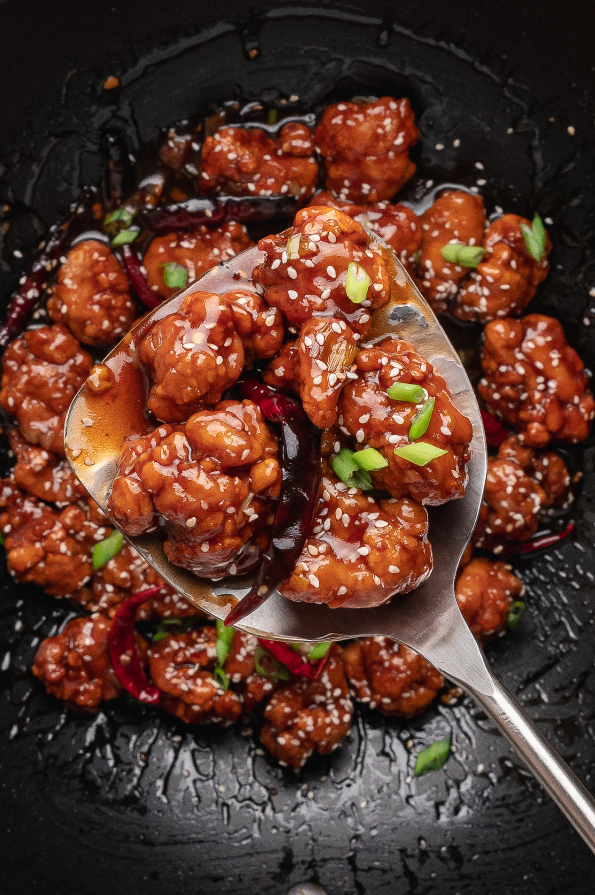 Close-up of crispy Chinese-American chicken tossed in glossy sweet and savory sauce with sesame seeds and scallions Close-up of crispy Chinese-American chicken tossed in glossy sweet and savory sauce with sesame seeds and scallions