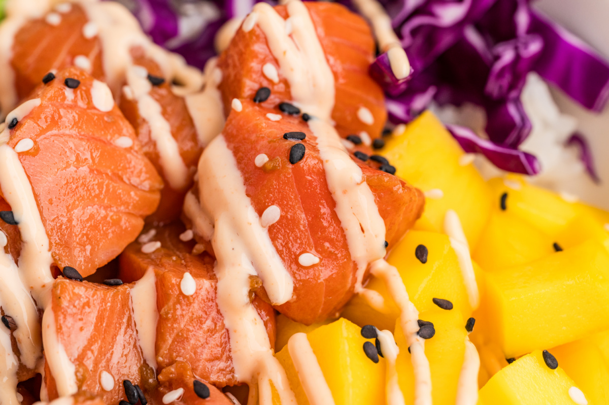 Salmon poke bowls with marinated raw salmon, mango, sesame seeds, and sriracha mayo