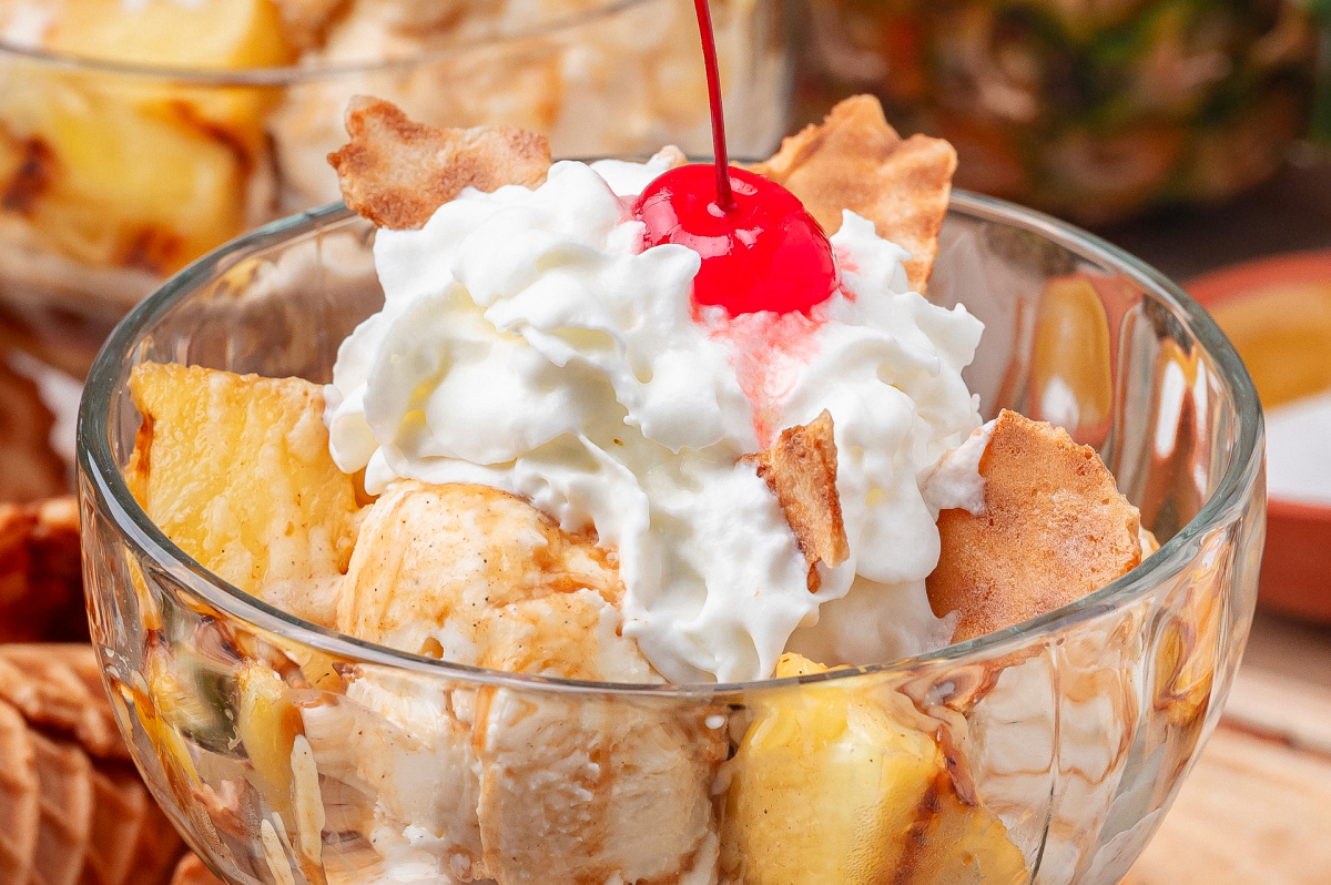 Hot Buttered Rum Grilled Pineapple Sundae Close up of grilled pineapple with vanilla ice cream, whipped cream, and hot buttered rum sauce