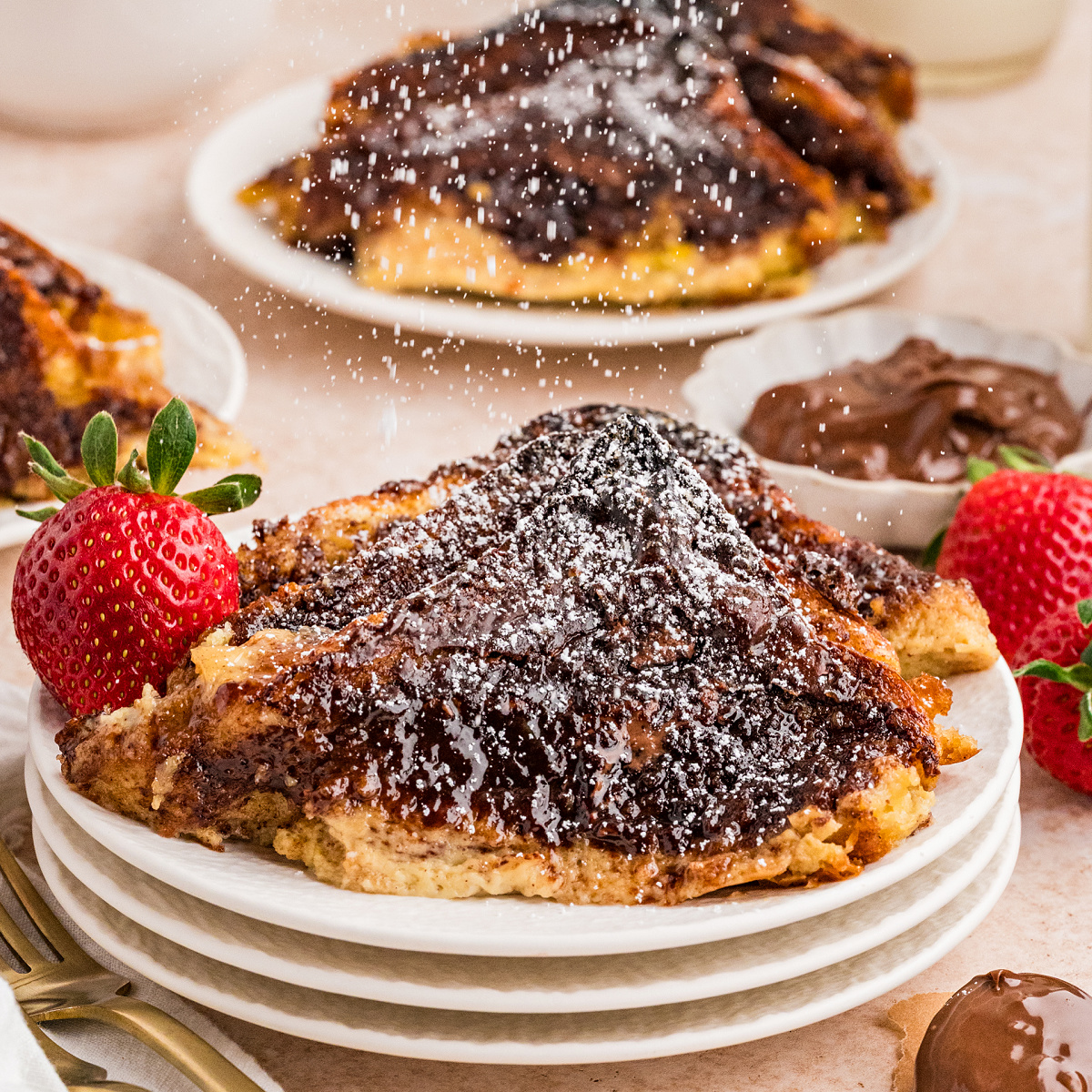 Slice of Nutella hazelnut French toast bake casserole dusted with powdered sugar and served with fresh strawberries