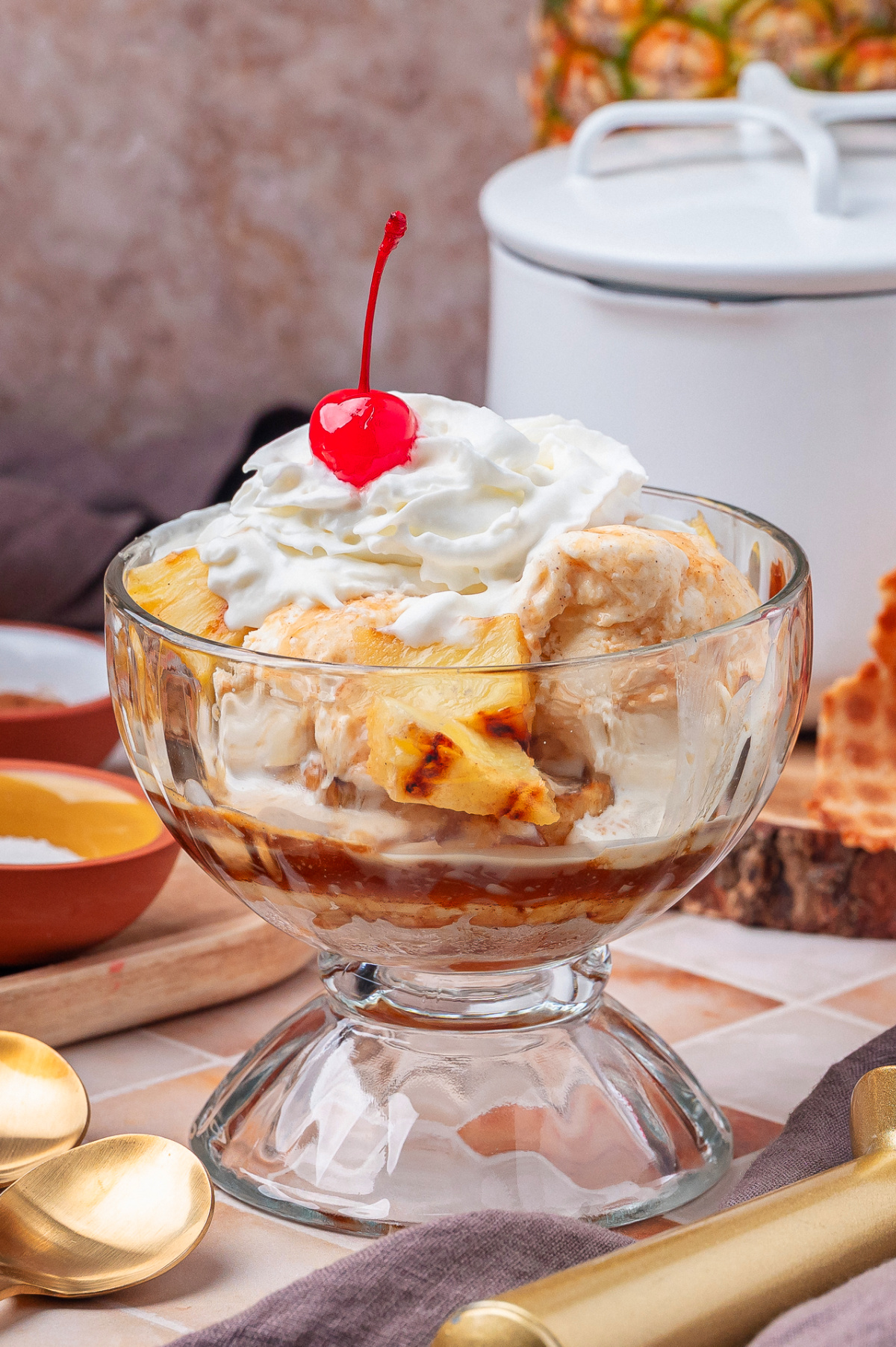 Rum Glazed Grilled Pineapple with Ice Cream Rum glazed grilled pineapple with vanilla ice cream, whipped cream, and cherry in a glass dessert bowl