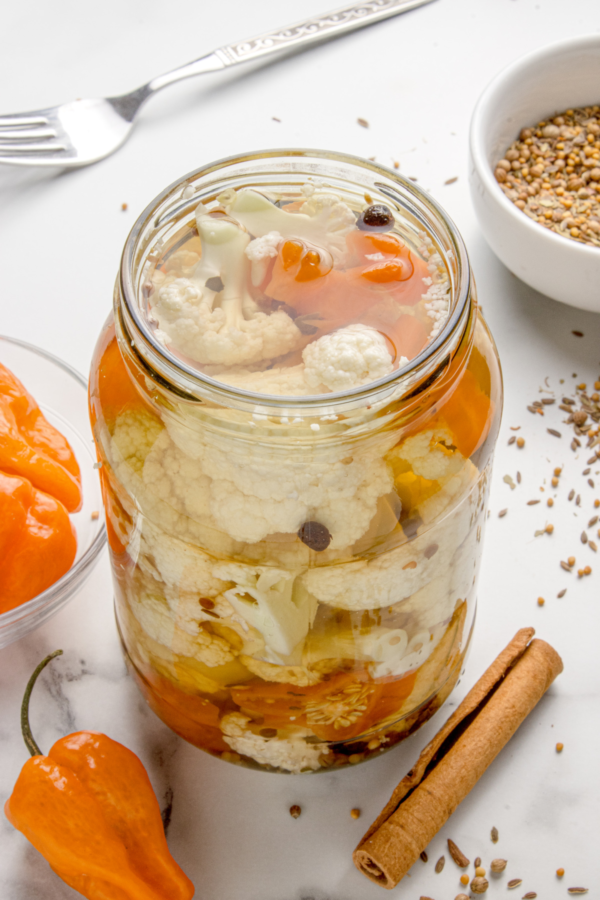 Hot pickled cauliflower in a mason jar with habanero peppers and whole spices in clear brine