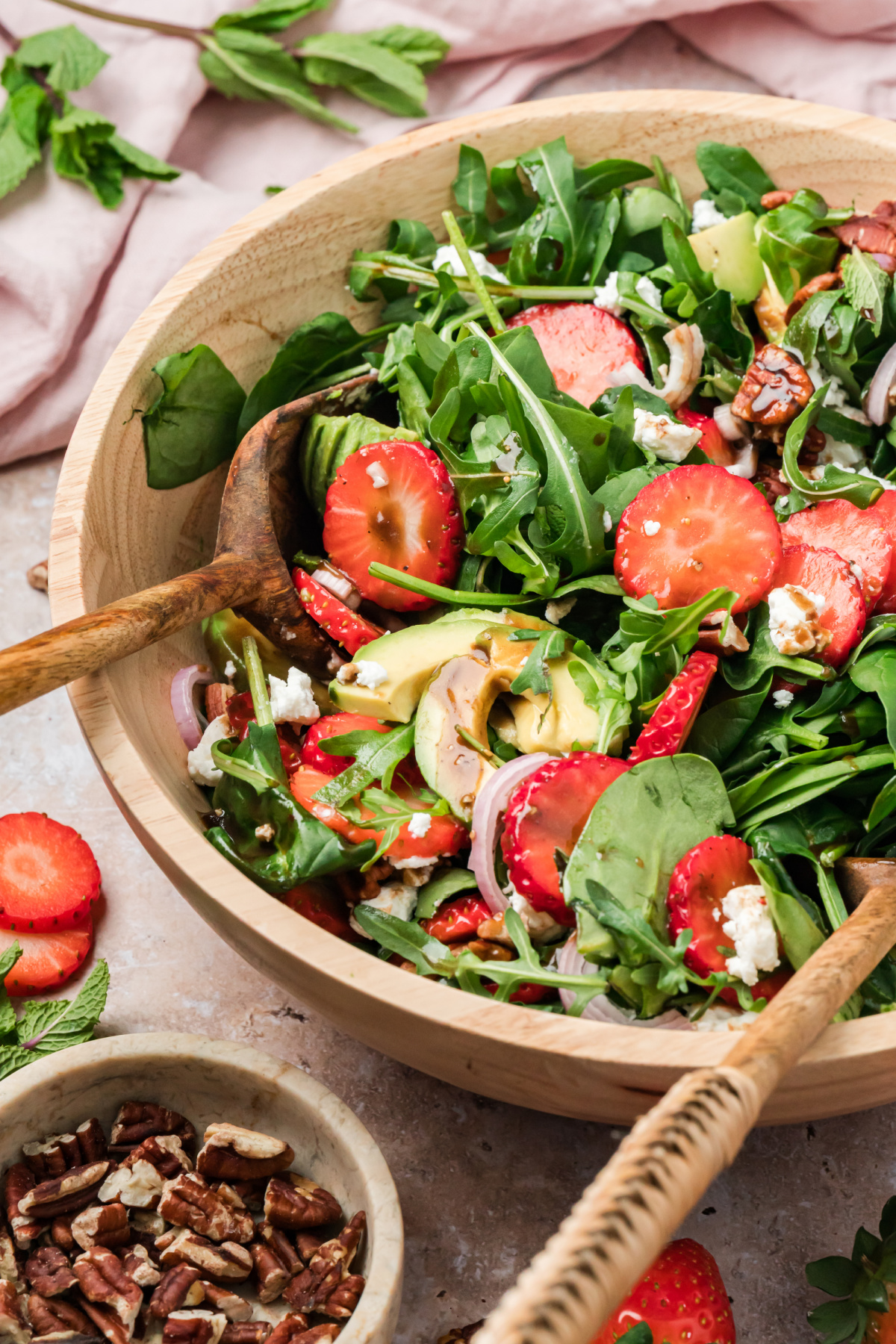 Strawberry Goat Cheese Salad with Avocado and Mixed Greens Strawberry goat cheese salad with avocado, pecans, and balsamic vinaigrette in a wooden bowl with spinach and arugula