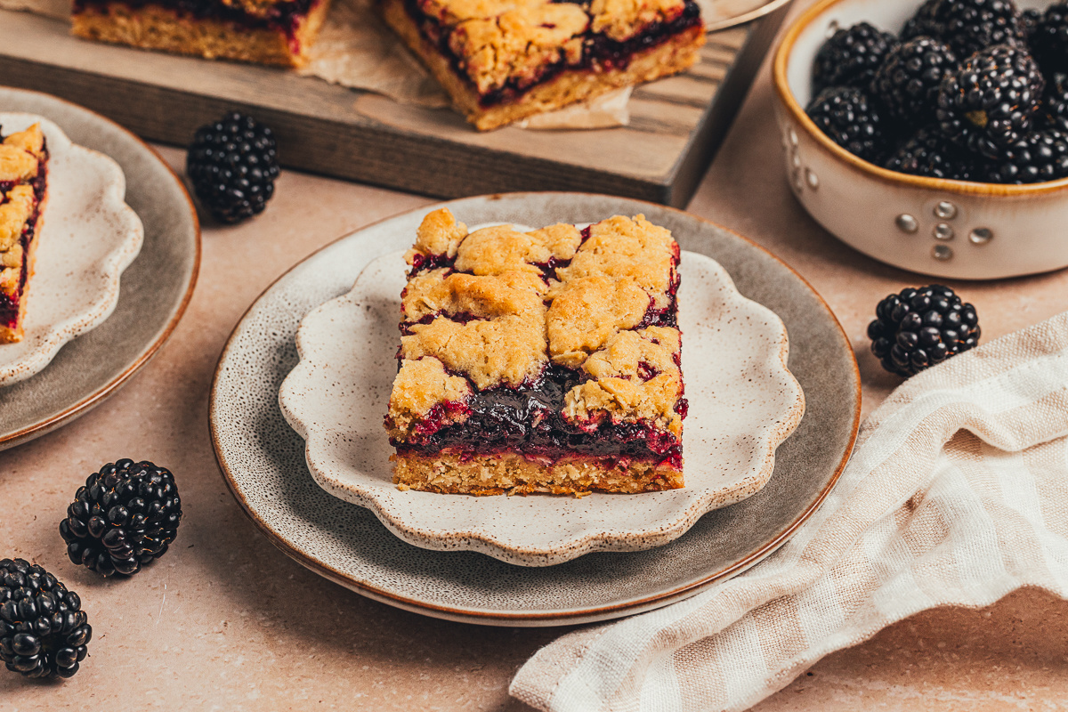 Blackberry crumble bar served on a plate with a rich blackberry layer blackberry crumble bar on a plate with oat topping and thick blackberry filling