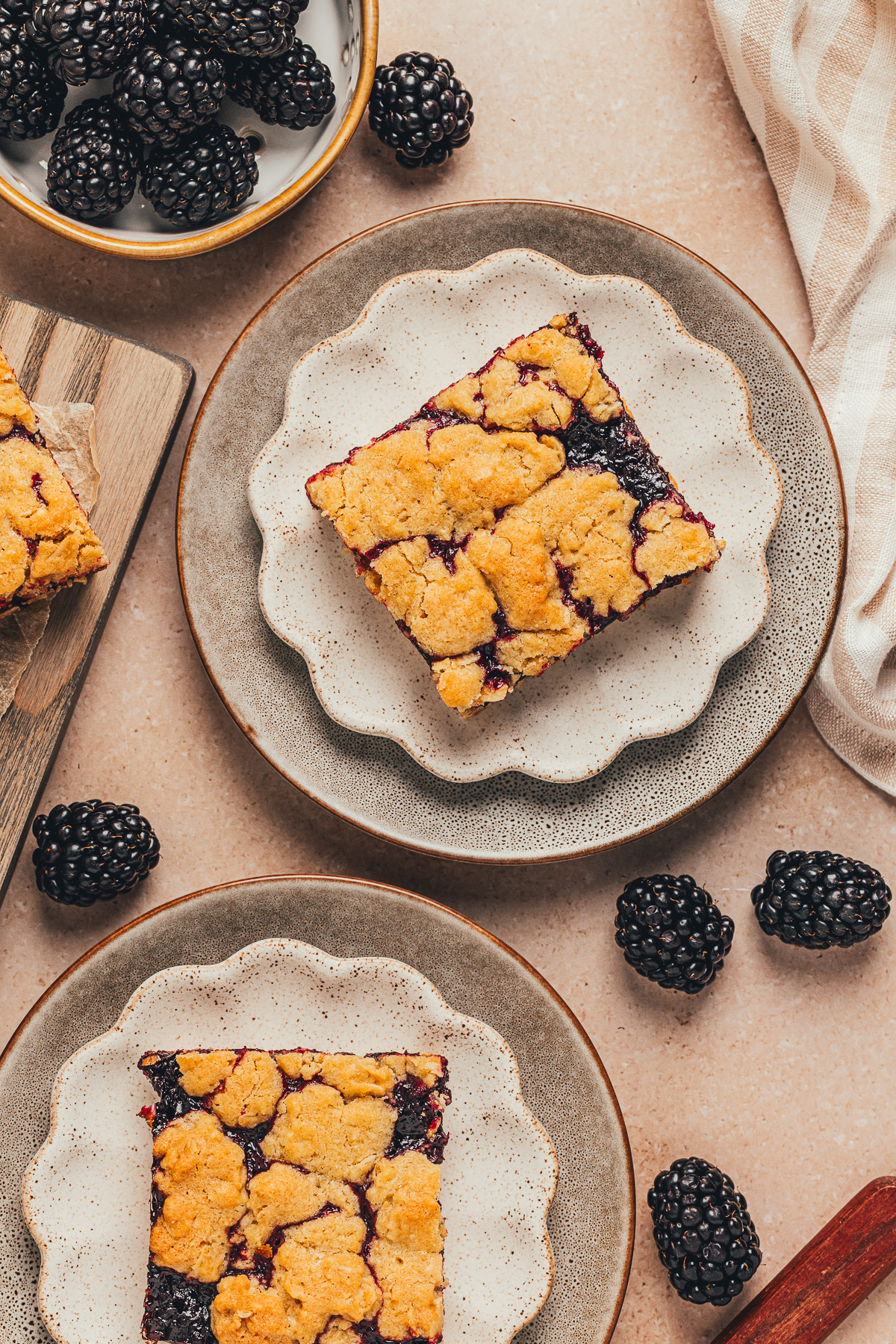 Blackberry crumble bars plated with a buttery oat topping and blackberry filling blackberry crumble bars served on plates with fresh blackberries around