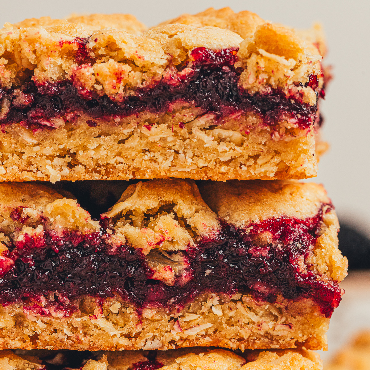 Blackberry crumble bars stacked with thick jam layer, oat crust, and crumb topping