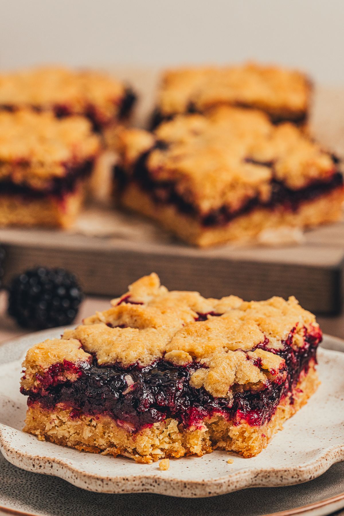 Close up of a blackberry oat crumble bar with a rich blackberry layer blackberry oat crumble bar close up showing thick blackberry filling and golden crumble topping