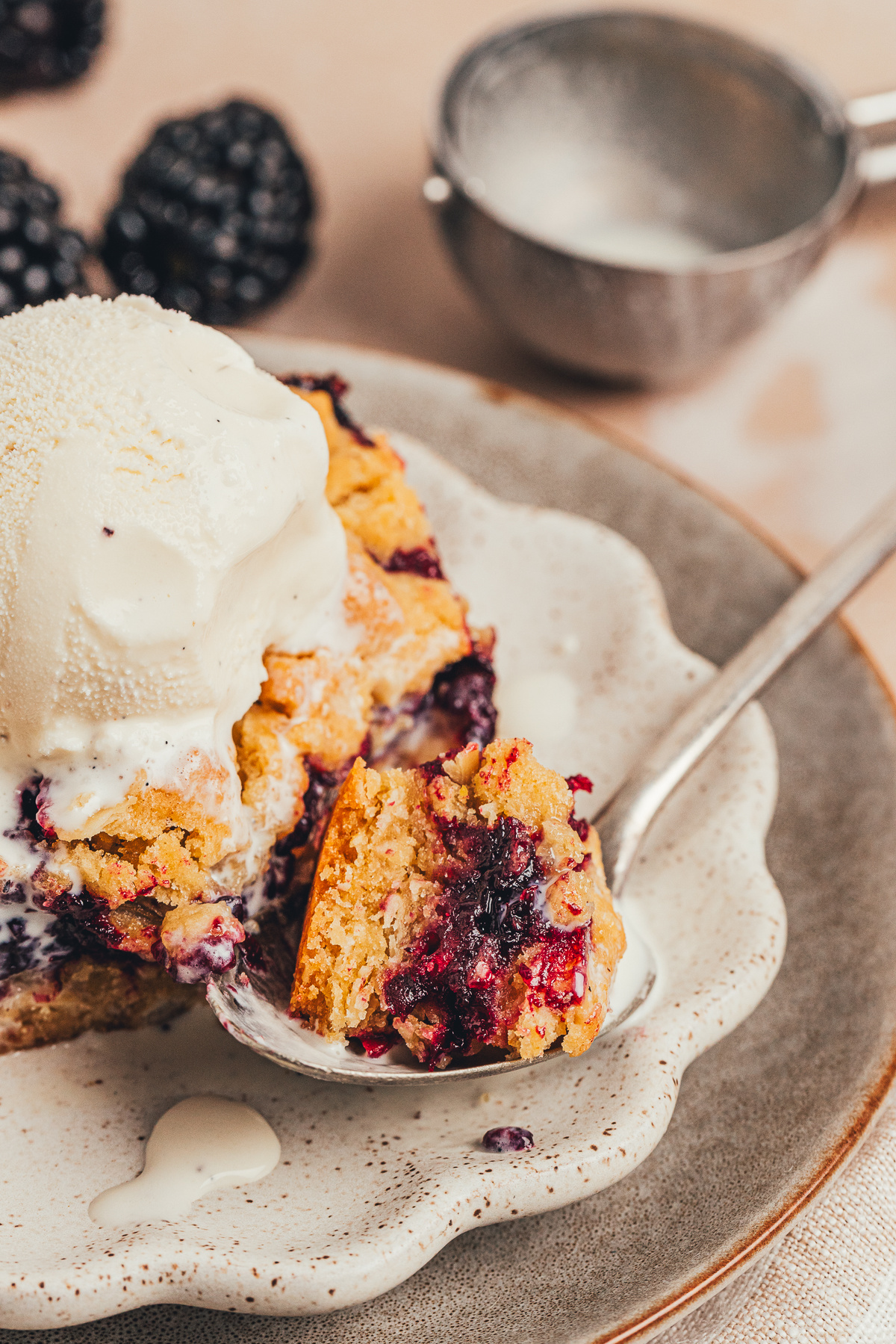 Blackberry oat crumble bar with vanilla ice cream and a spoonful taken bite of blackberry oat crumble bar with vanilla ice cream and spoon