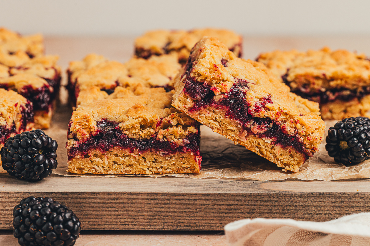 Blackberry oat crumble bars with a thick fruit layer and fresh blackberries blackberry oat crumble bars cut into squares with fresh blackberries on the side