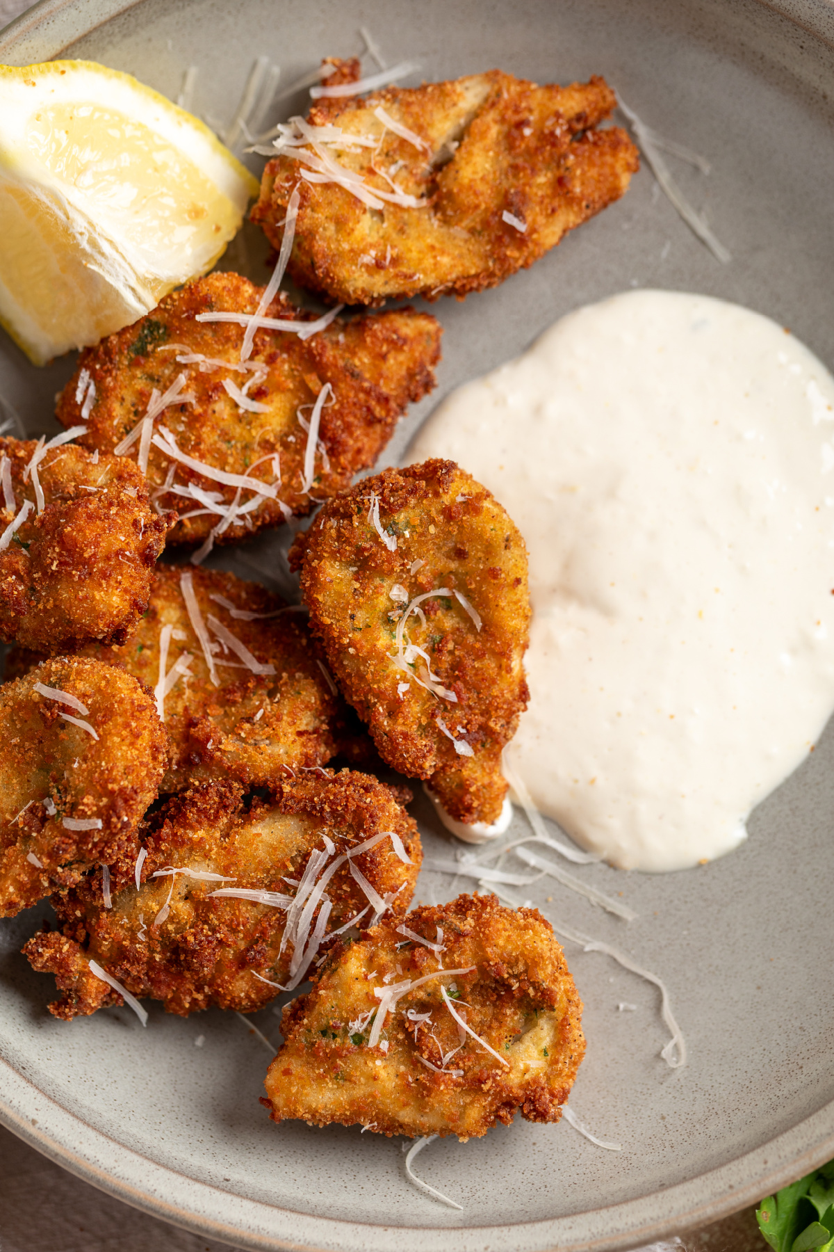 Breaded artichokes with creamy lemon garlic aioli and Parmesan Crispy breaded artichoke hearts served with lemon garlic aioli and grated Parmesan on a plate