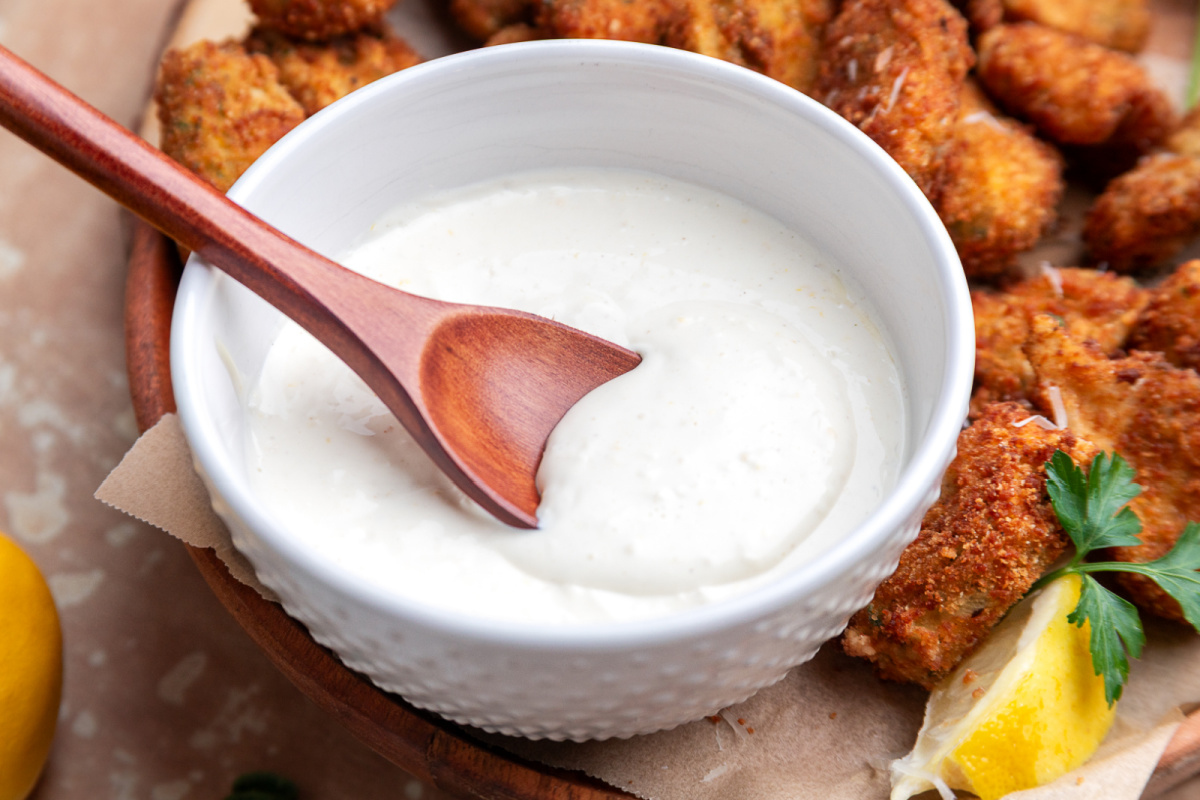 Lemon garlic aioli dipping sauce served with crispy fried artichokes Fried artichokes with lemon garlic aioli in a white bowl with a spoon and lemon wedge