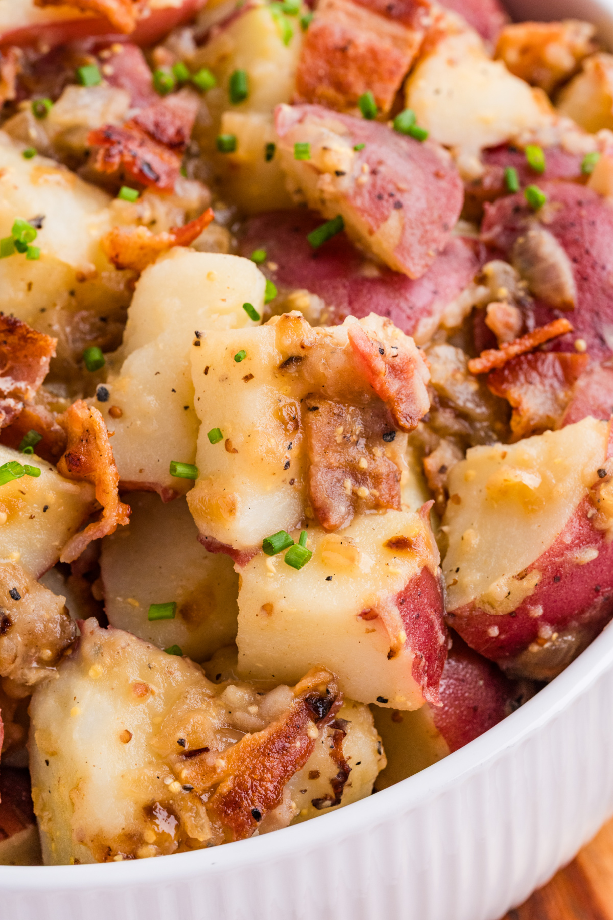 German potato salad with bacon, red potatoes, and whole grain mustard dressing garnished with chives