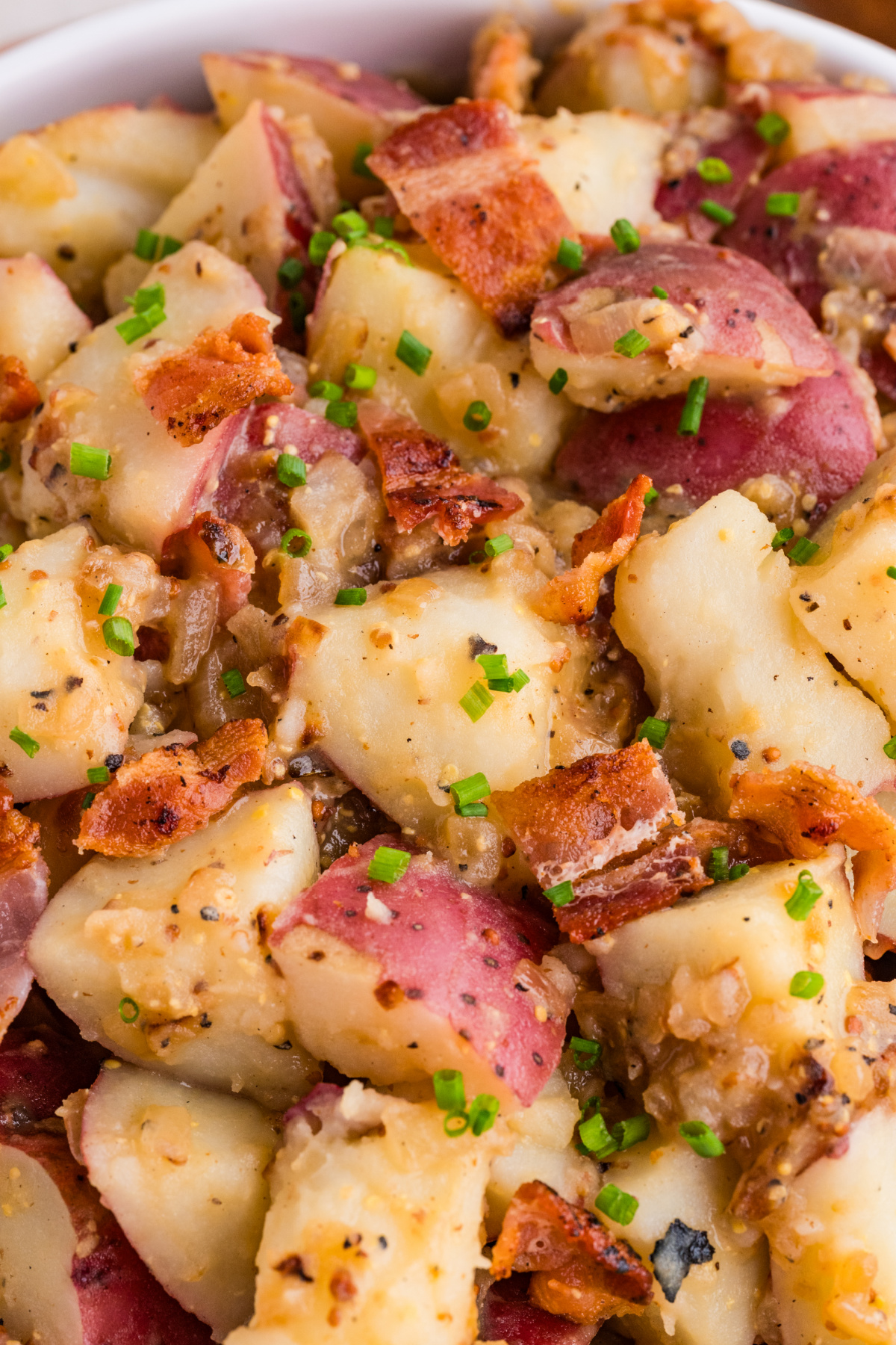 German potato salad close-up with bacon, red potatoes, whole grain mustard, and chives