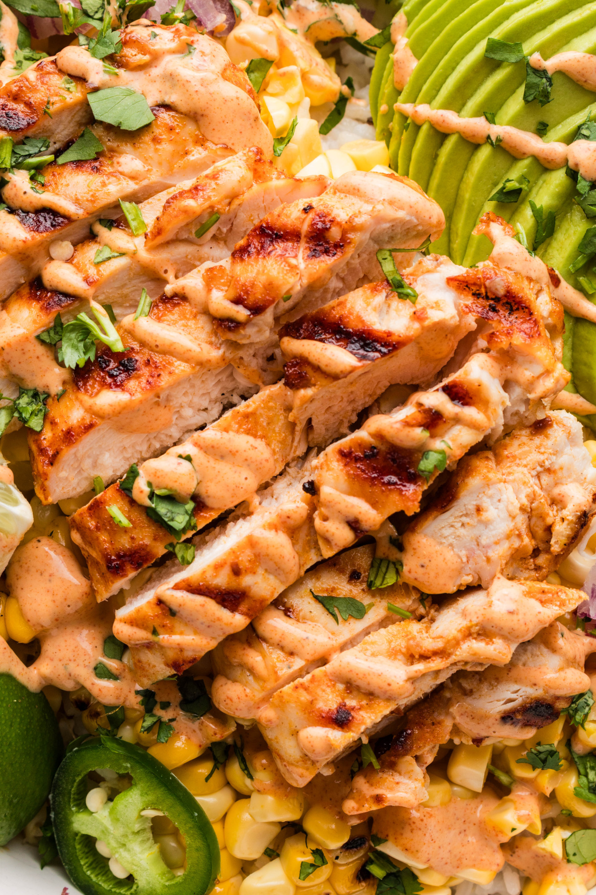 grilled chicken with corn and creamy lime sauce closeup grilled chicken slices with charred corn, jalapeños, avocado, and creamy elote-style sauce over rice