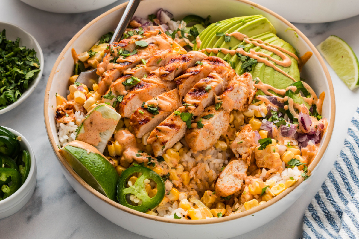 chicken rice bowl with corn, avocado, and lime crema grilled chicken rice bowl with charred corn, avocado slices, jalapeños, red onion, and creamy elote-style sauce