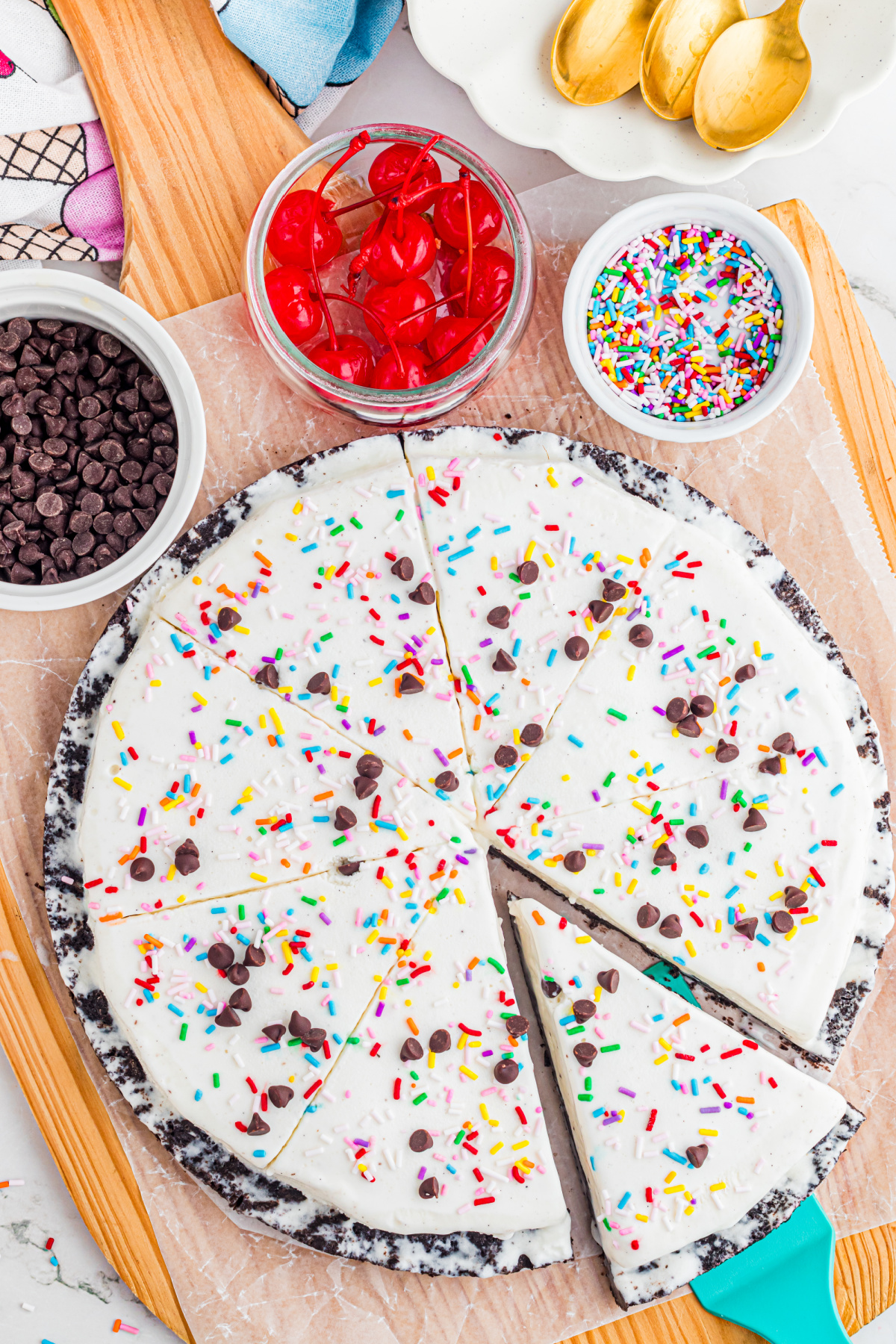 Ice Cream Pizza with Oreo Crust and Toppings ice cream pizza sliced into wedges with Oreo crust, sprinkles, and chocolate chips