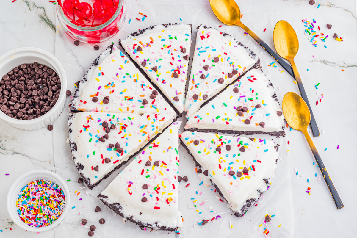 Overhead Ice Cream Pizza with Sprinkles and Chocolate Chips overhead ice cream pizza with Oreo crust cut into slices with sprinkles and chocolate chips