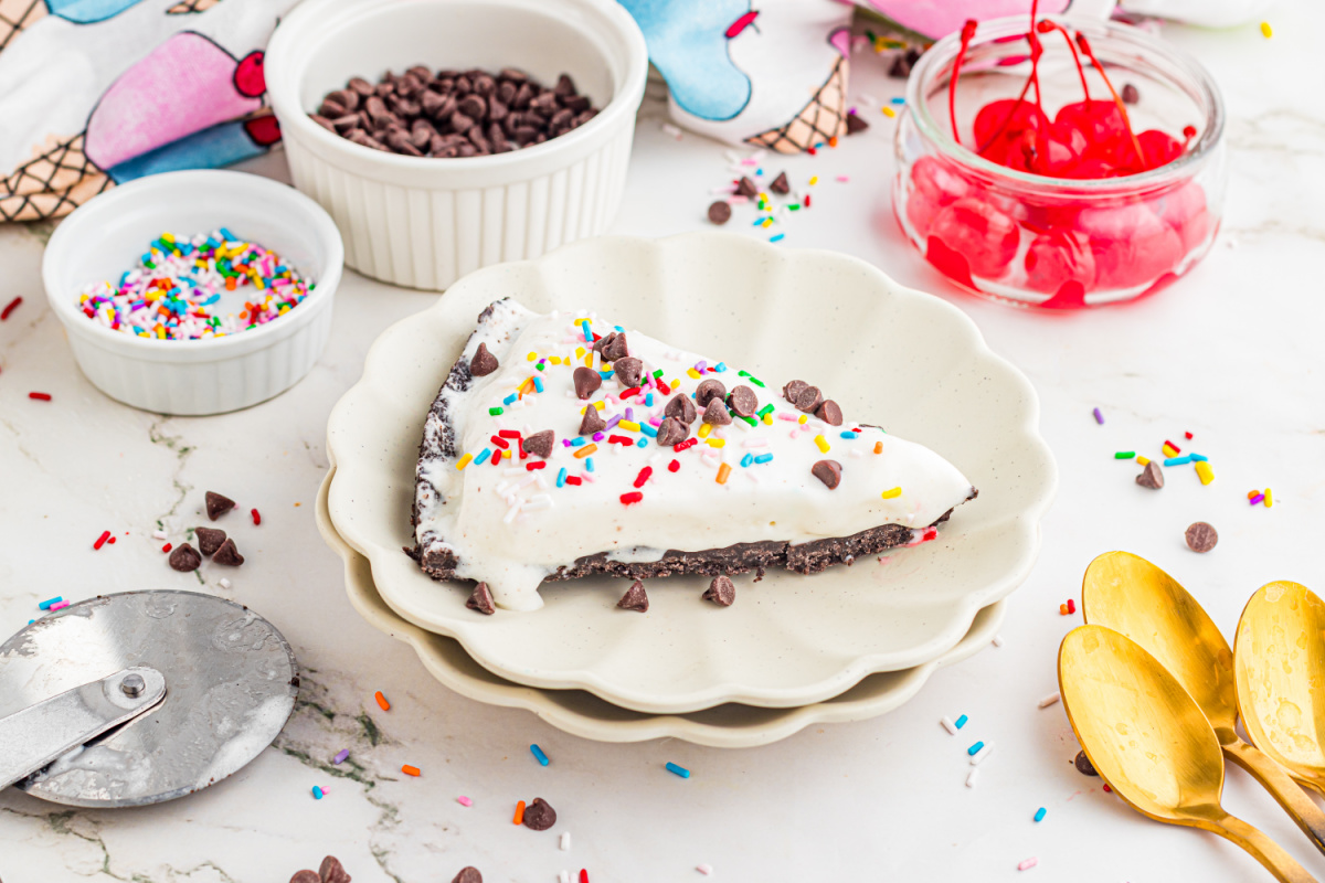 Ice Cream Pizza Slice with Oreo Crust and Toppings slice of ice cream pizza on a plate with Oreo crust, sprinkles, and chocolate chips