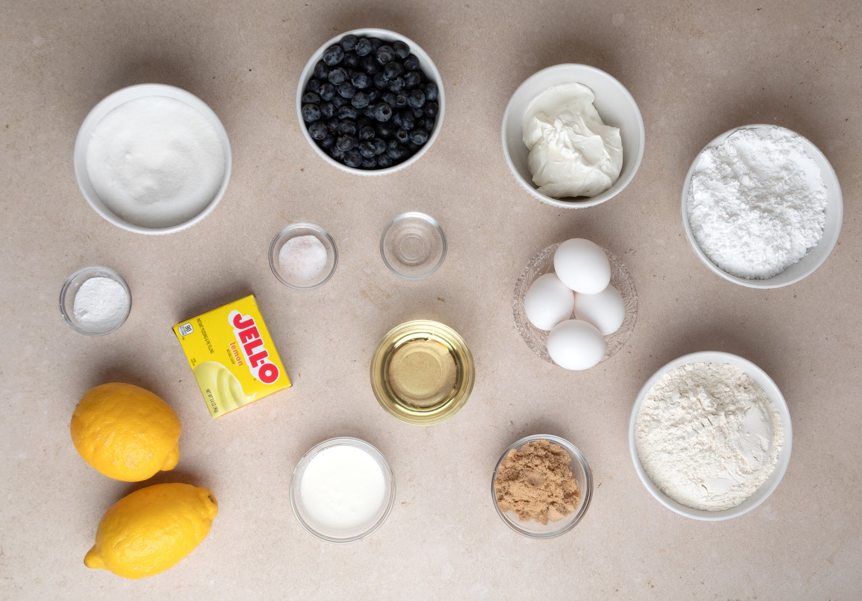 ingredients for lemon blueberry bundt cake with sour cream and pudding mix ingredients for lemon blueberry bundt cake including flour, sugar, eggs, sour cream, blueberries, and lemon pudding mix