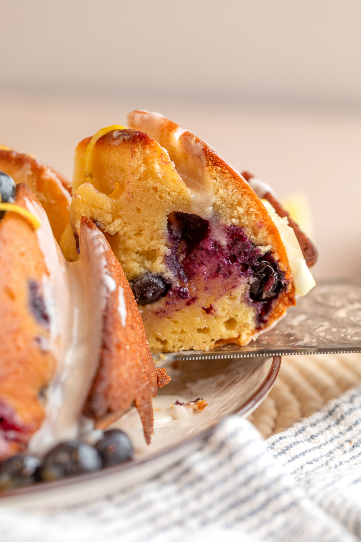 inside of lemon blueberry bundt cake with blueberries and glaze slice of lemon blueberry bundt cake showing interior with baked blueberries and lemon glaze