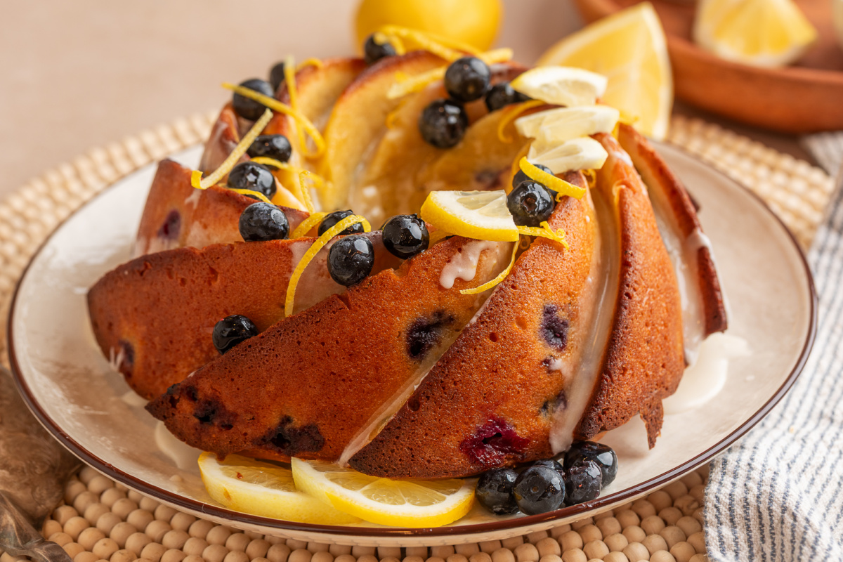 sliced lemon blueberry bundt cake with glaze and fresh blueberries sliced lemon blueberry bundt cake with lemon glaze, fresh blueberries, and lemon slices on a plate