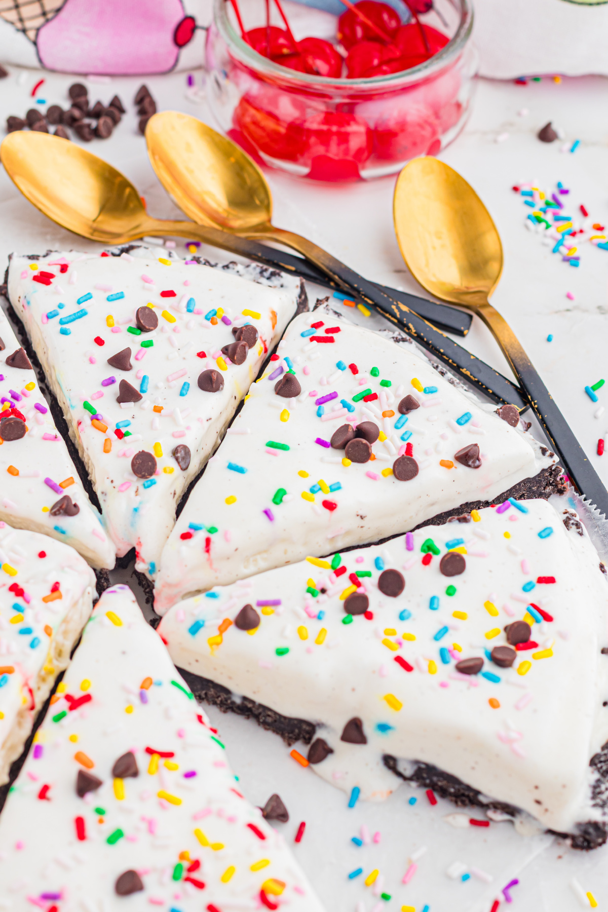 No-Bake Ice Cream Pizza Slices with Oreo Crust no bake ice cream pizza slices with Oreo crust, sprinkles, and chocolate chips on a platter