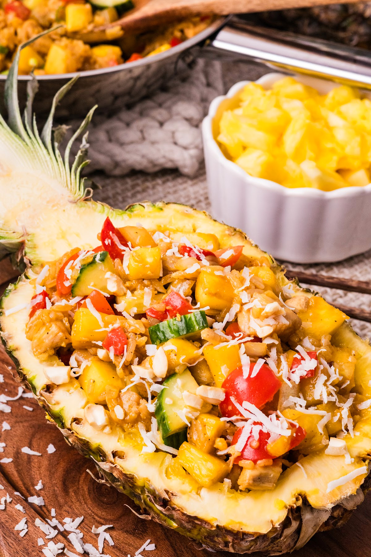 pineapple chicken and rice served in a pineapple bowl with coconut rice, chicken, and fresh vegetables