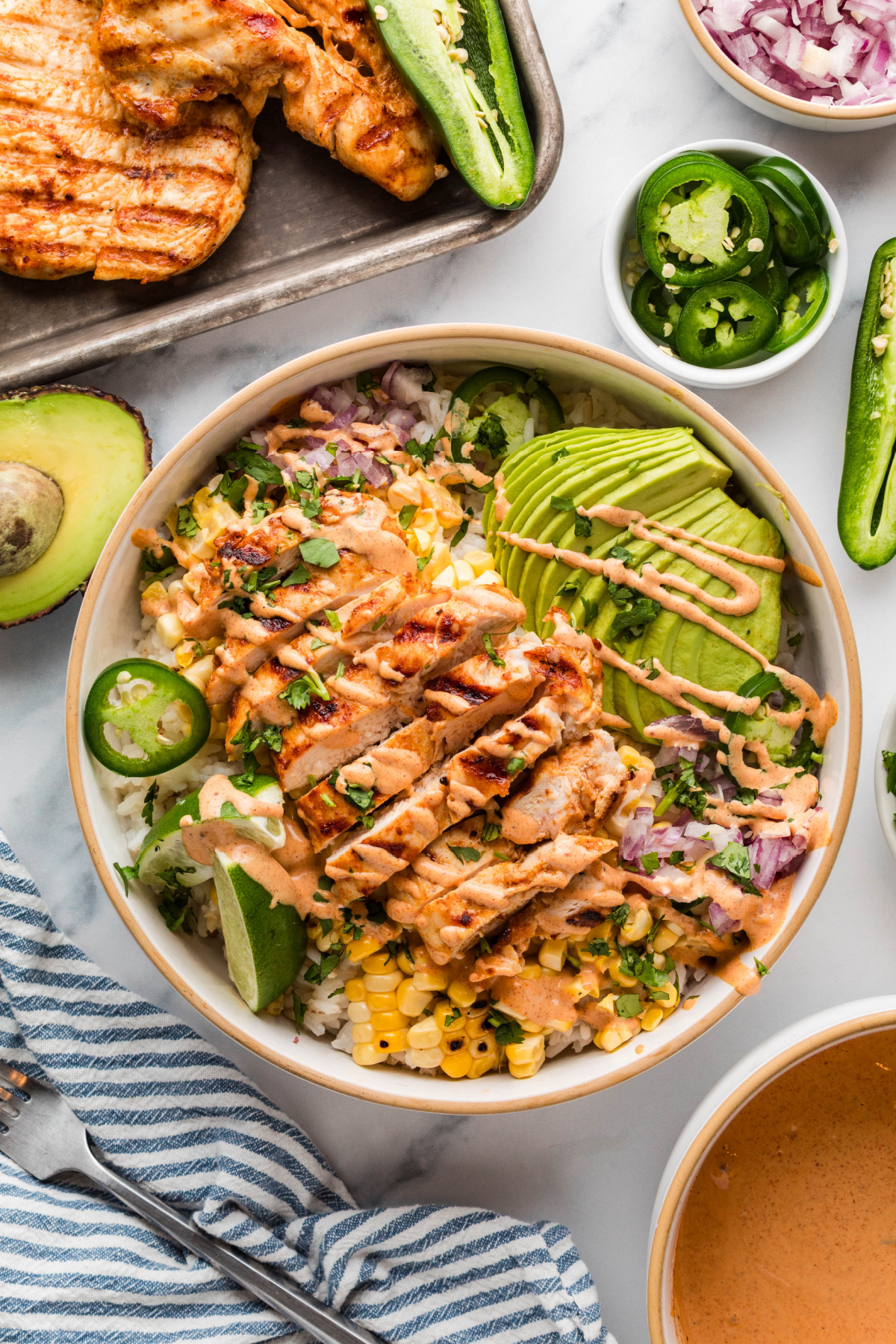 Grilled chicken rice bowl with street corn, avocado, and lime crema Street corn chicken rice bowls with grilled chicken, charred corn, avocado, and creamy elote-style sauce over rice