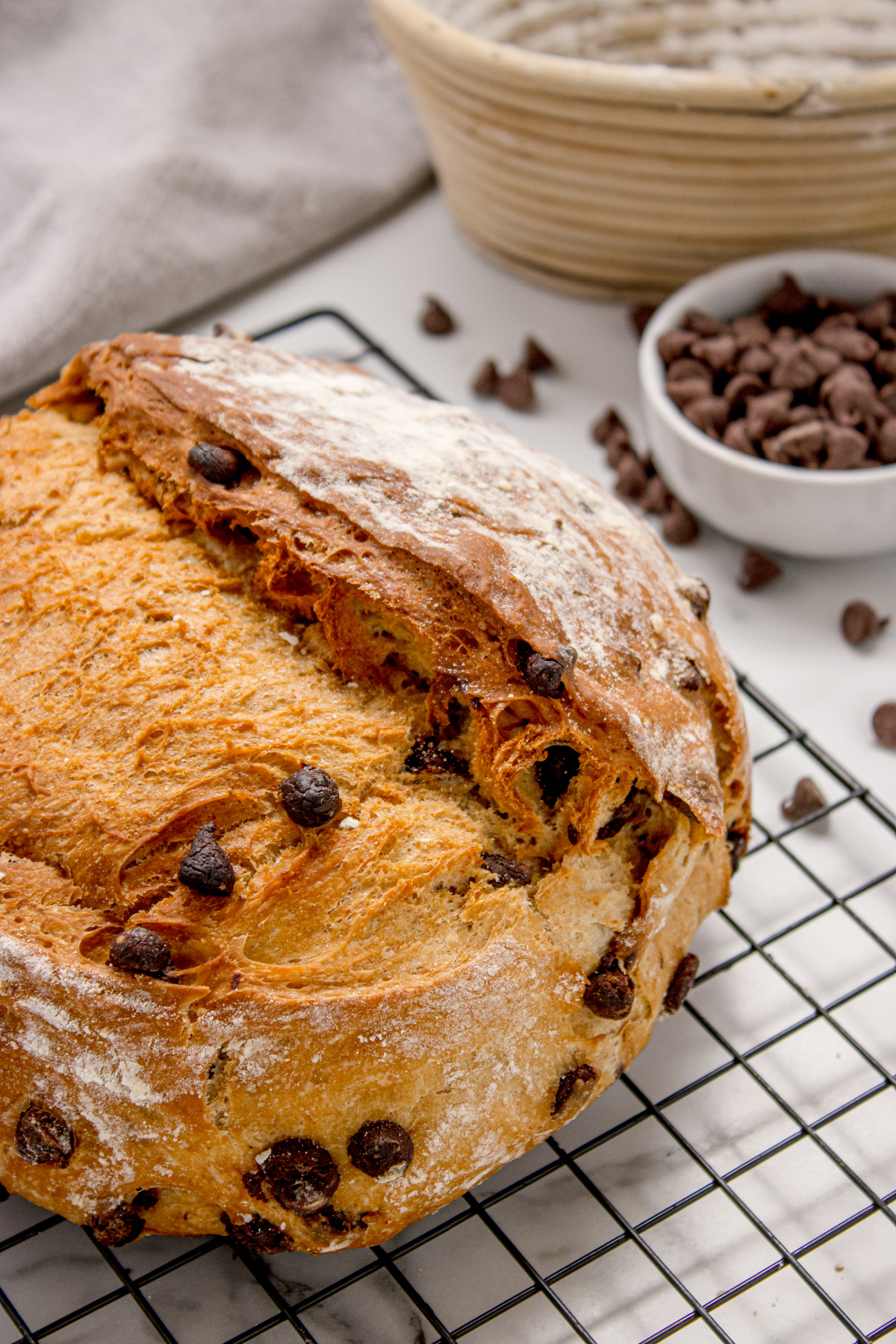 Crusty loaf just cut open with chocolate chips baked into the dough Chocolate Chip Artisan Bread sliced open on a cooling rack showing golden crust and melted chocolate chips inside
