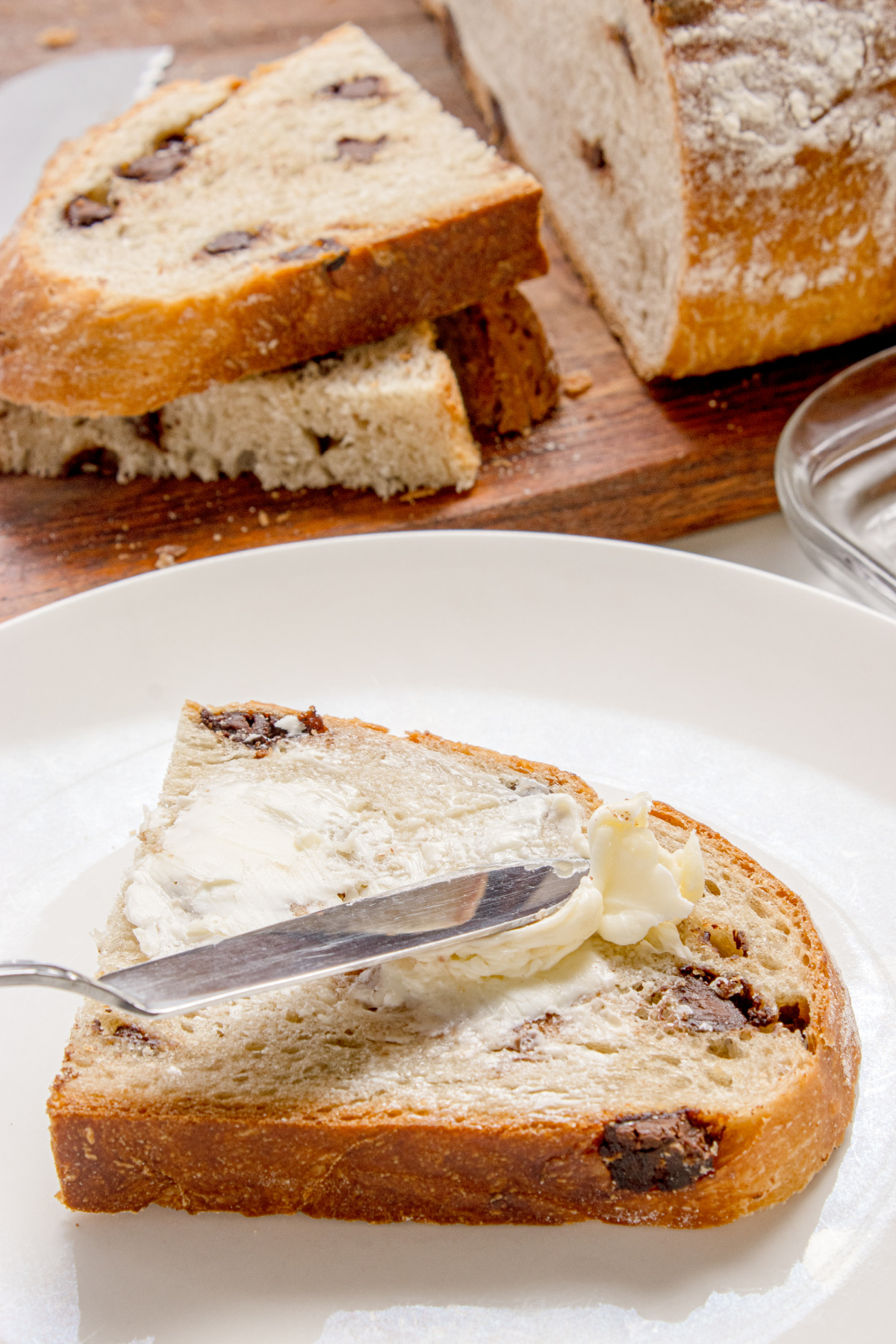 bread slice with butter spread showing how it’s served slice of chocolate chip bread with butter spread on top on a plate